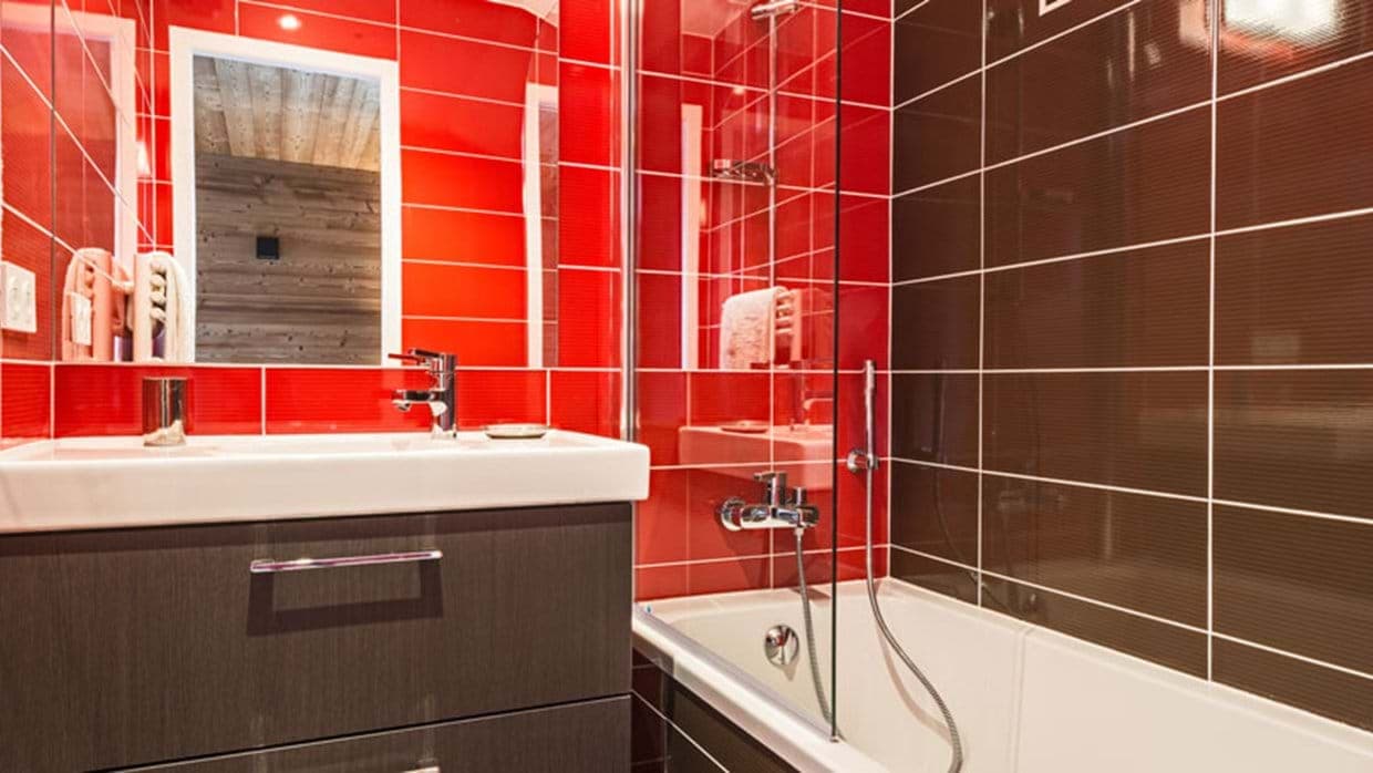 Bathroom featuring soaking tub with shower wand and glass partition