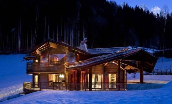 Chalet exterior at night with wrap-around decks and mountain forest backdrop