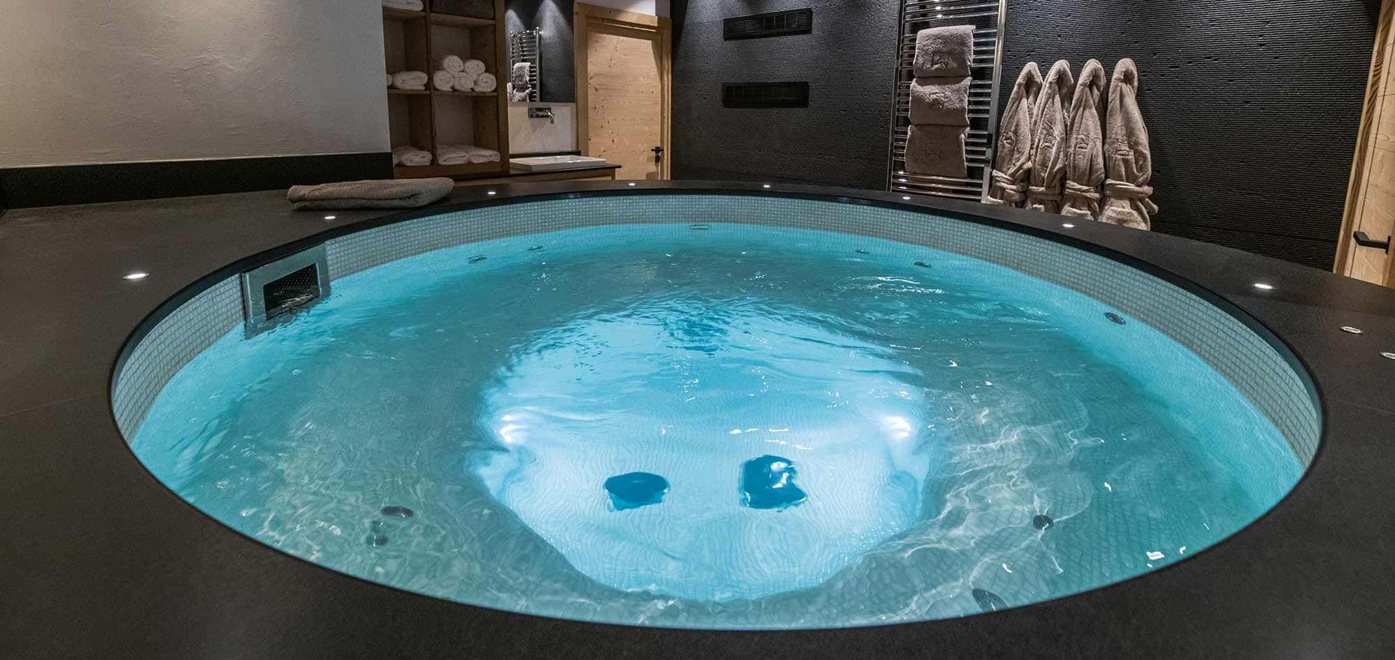 Indoor circular hot tub with heated towel racks and provided robes