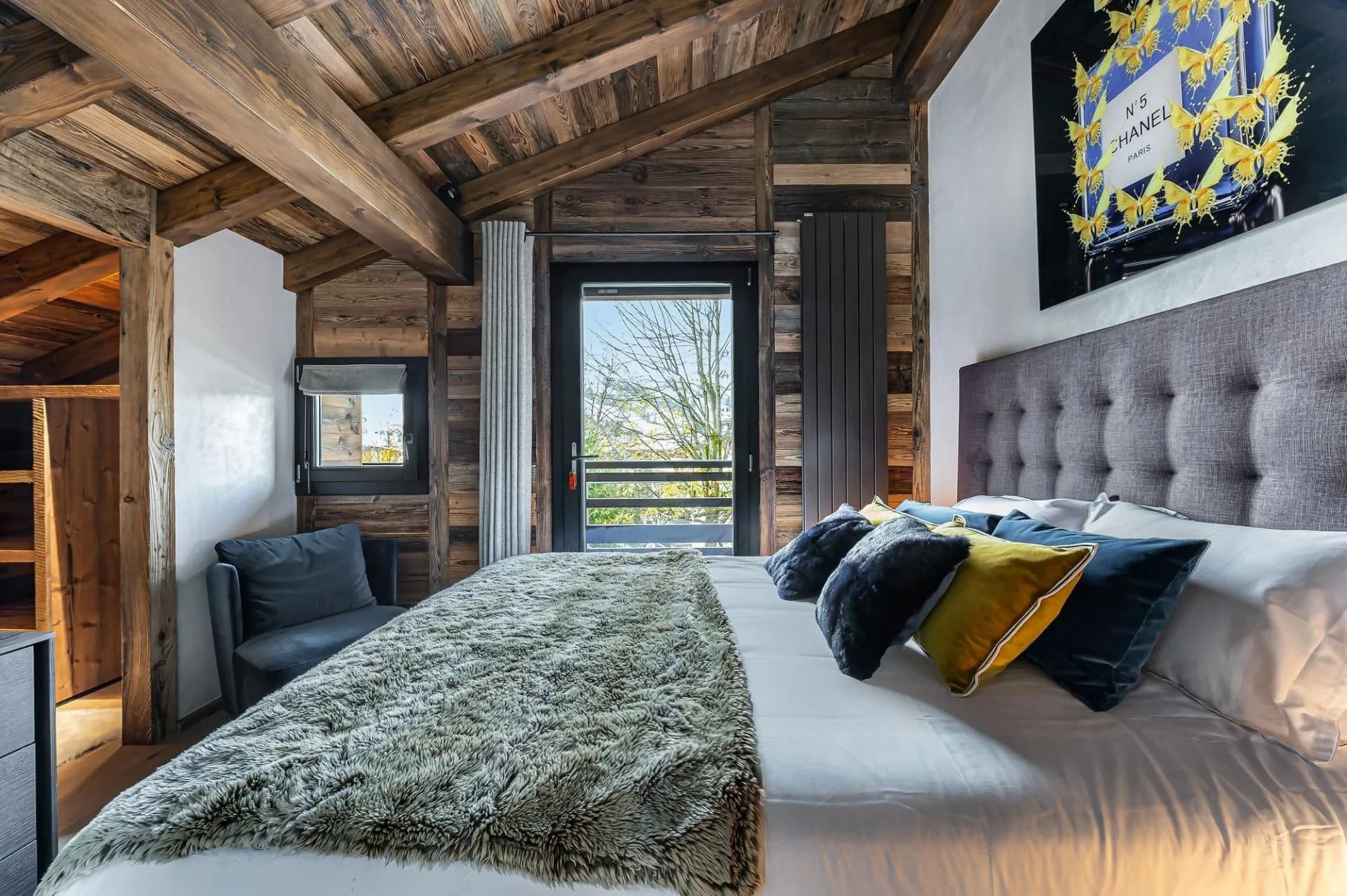 Double bedroom beneath a vaulted timber ceiling with balcony access