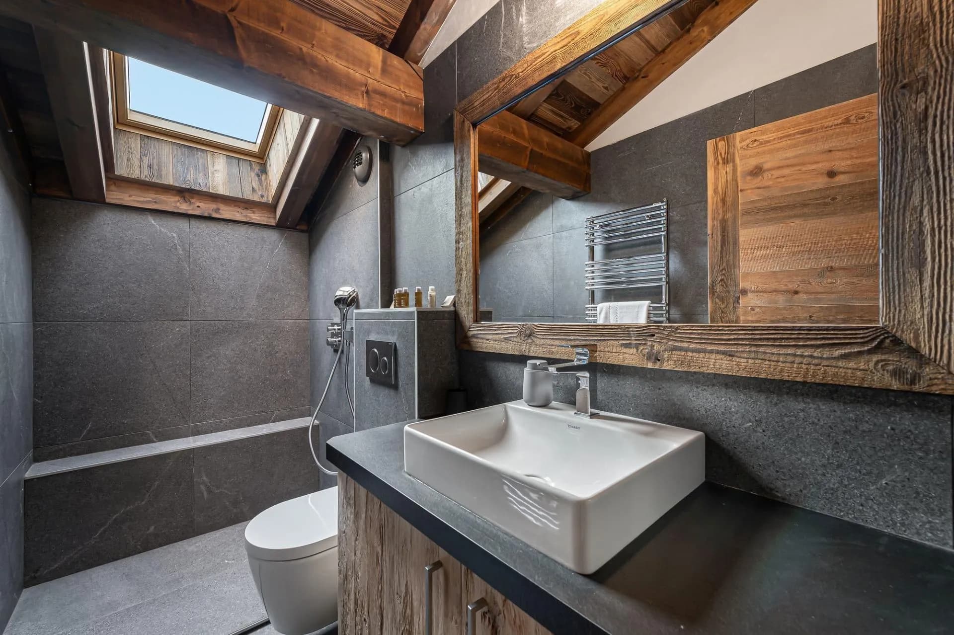En-suite shower room with stone tiling and heated towel rail