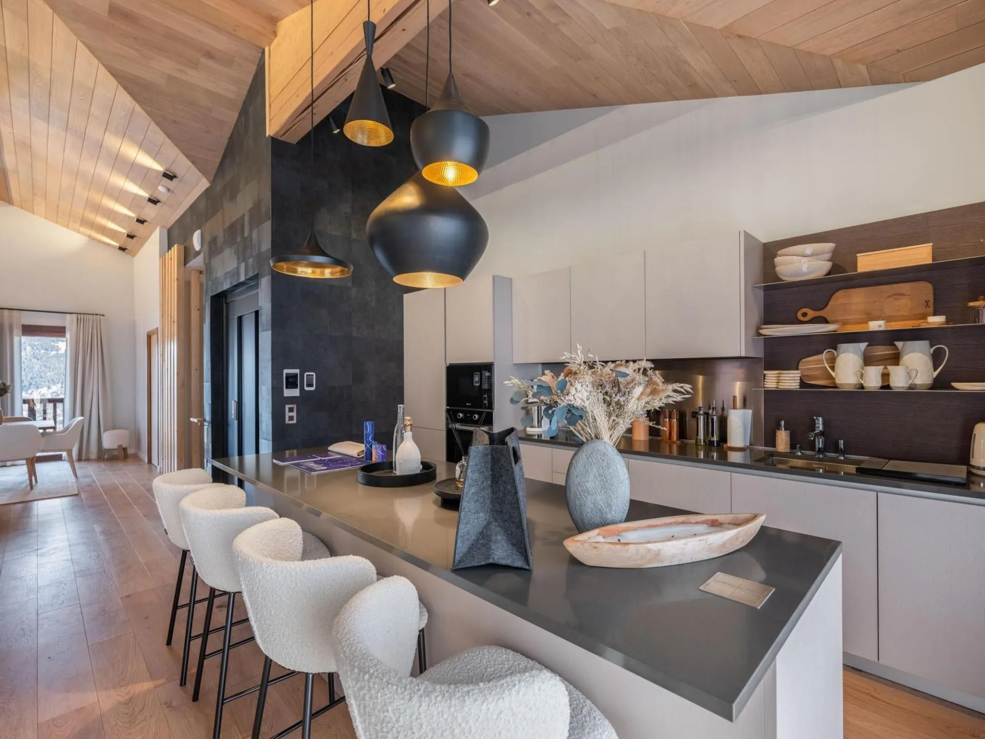 Kitchen island with bar stools beneath a timber ceiling