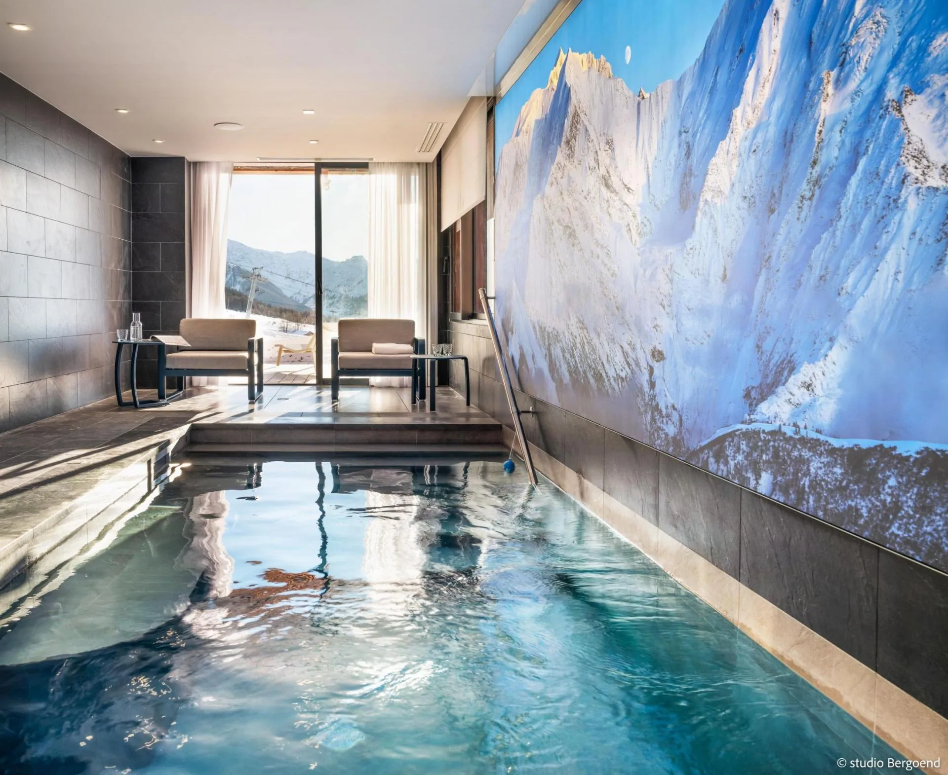 Indoor swimming pool with mountain mural and terrace doors