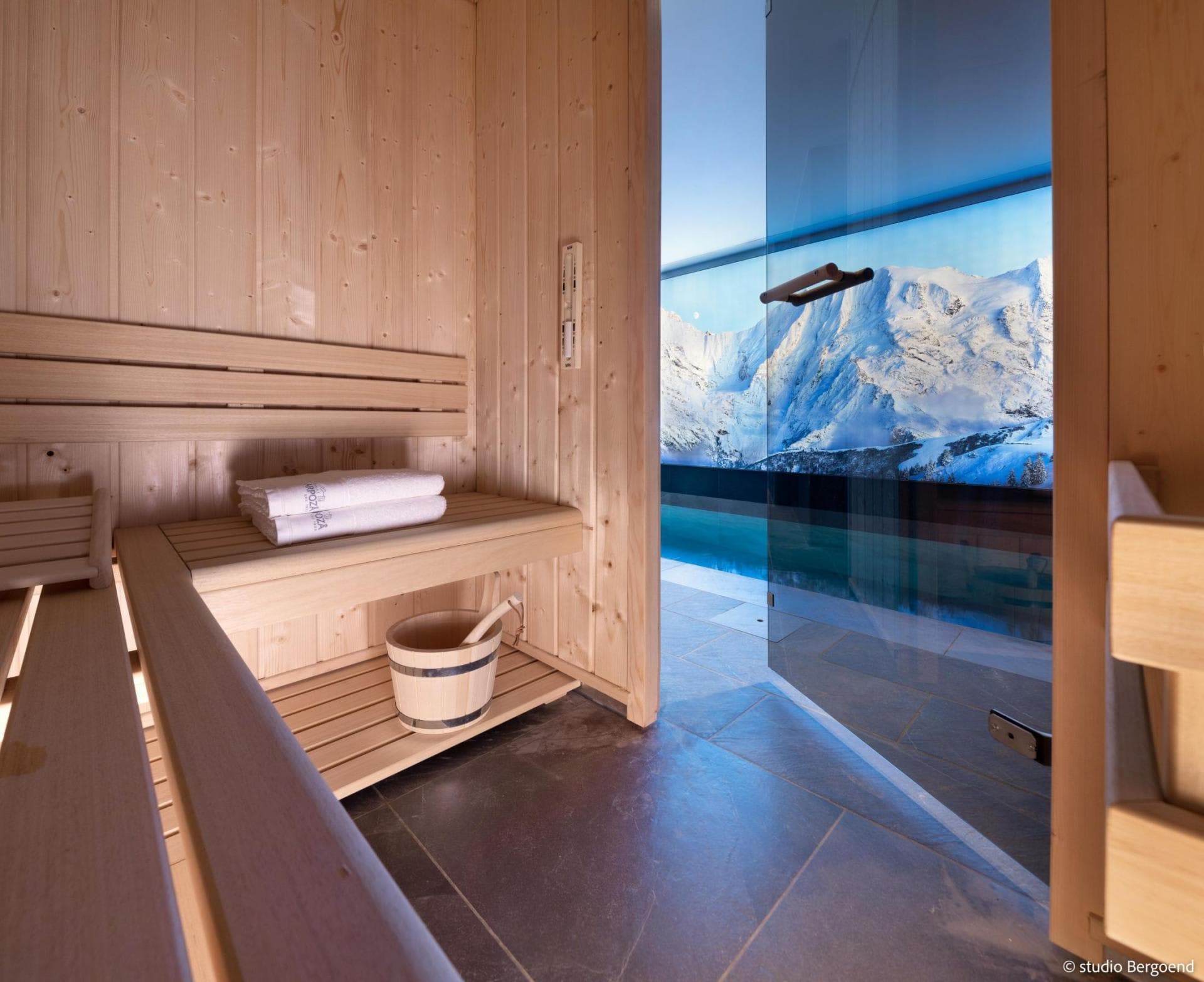 Cedar sauna with glass door opening to indoor pool and mountain views