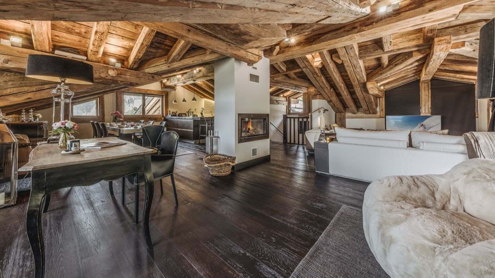 Open-plan living area with vaulted timber beams and double-sided fireplace