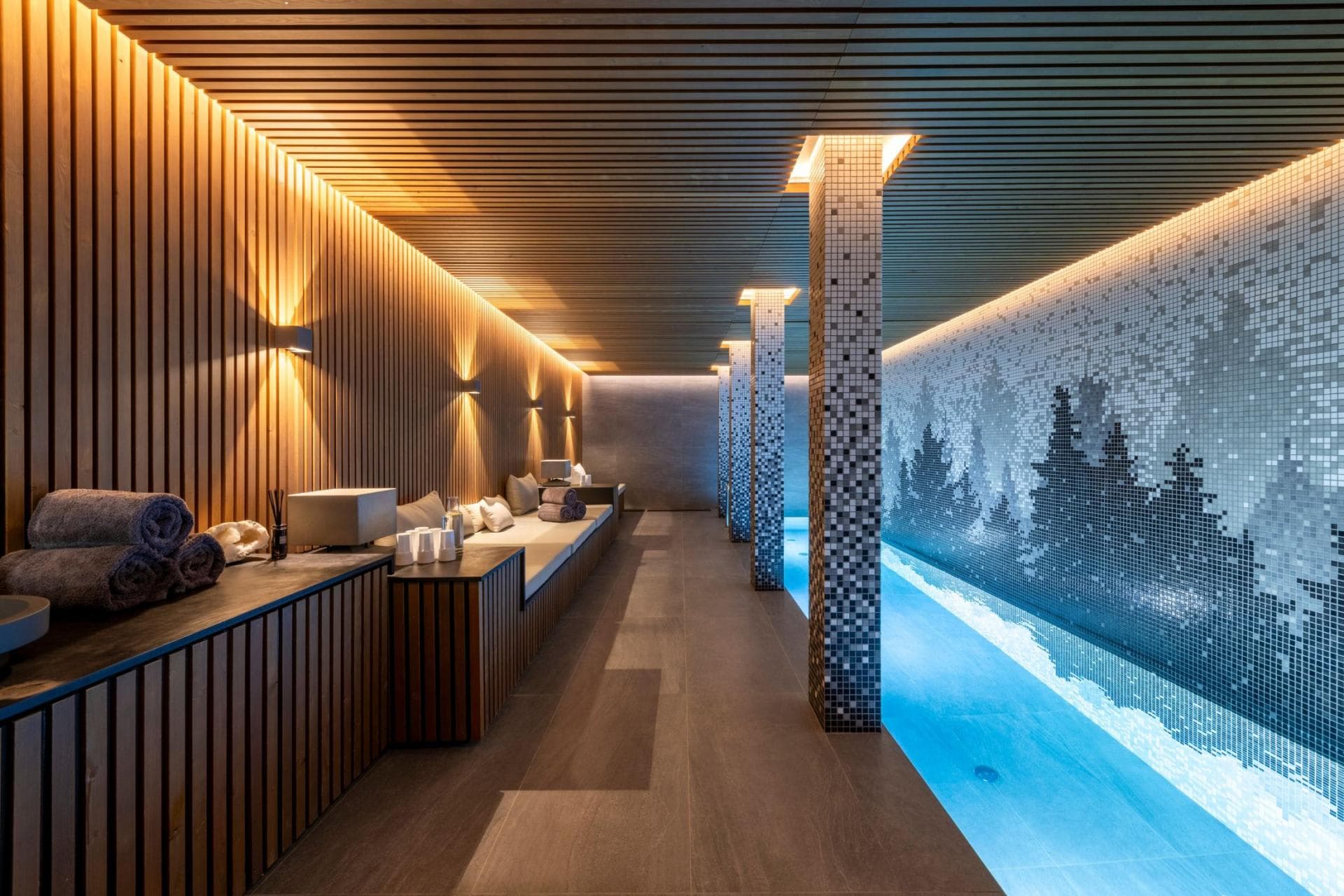 Indoor lap pool with bench seating and mosaic forest mural