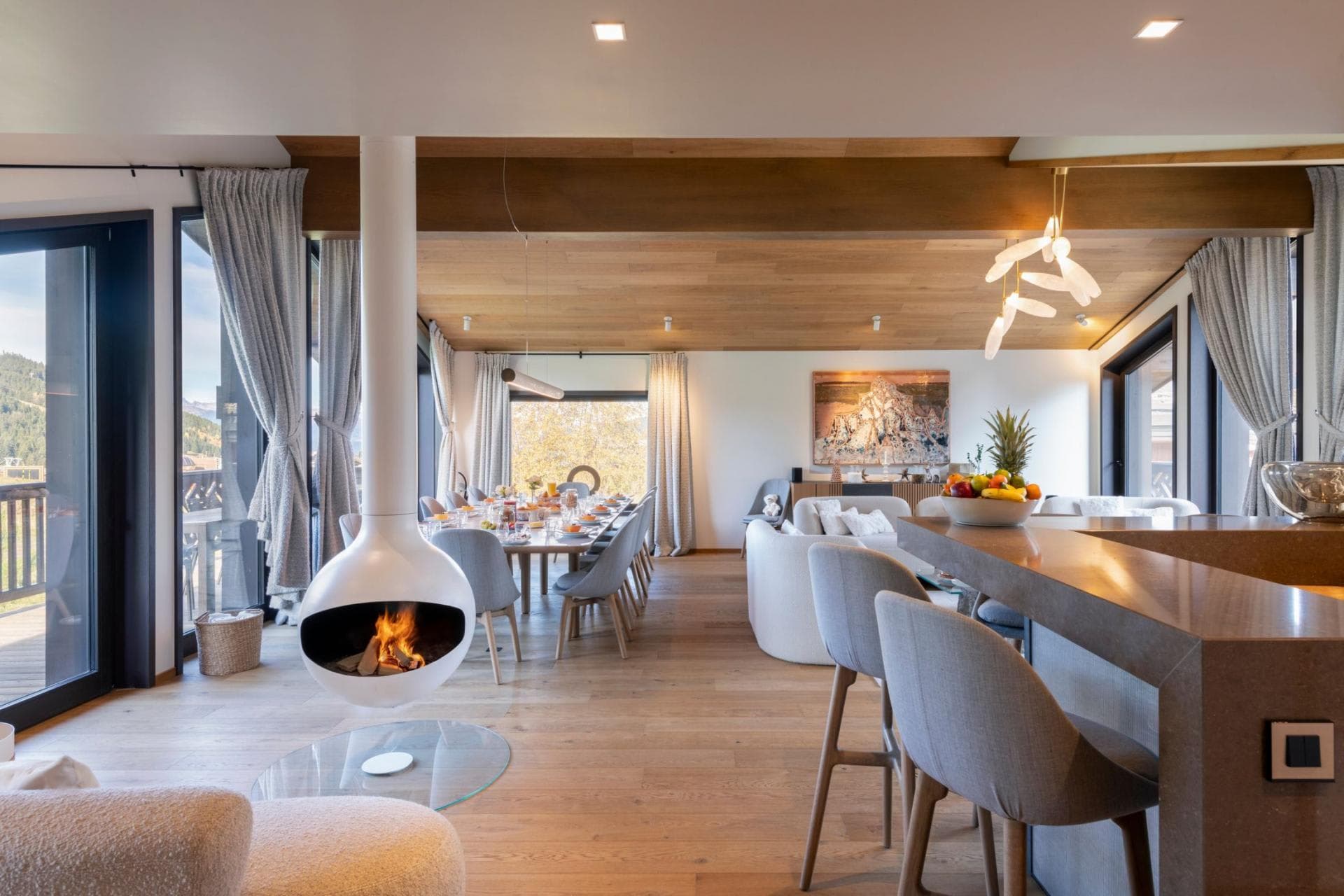 Open-plan living area with suspended fireplace and dining table seating 10