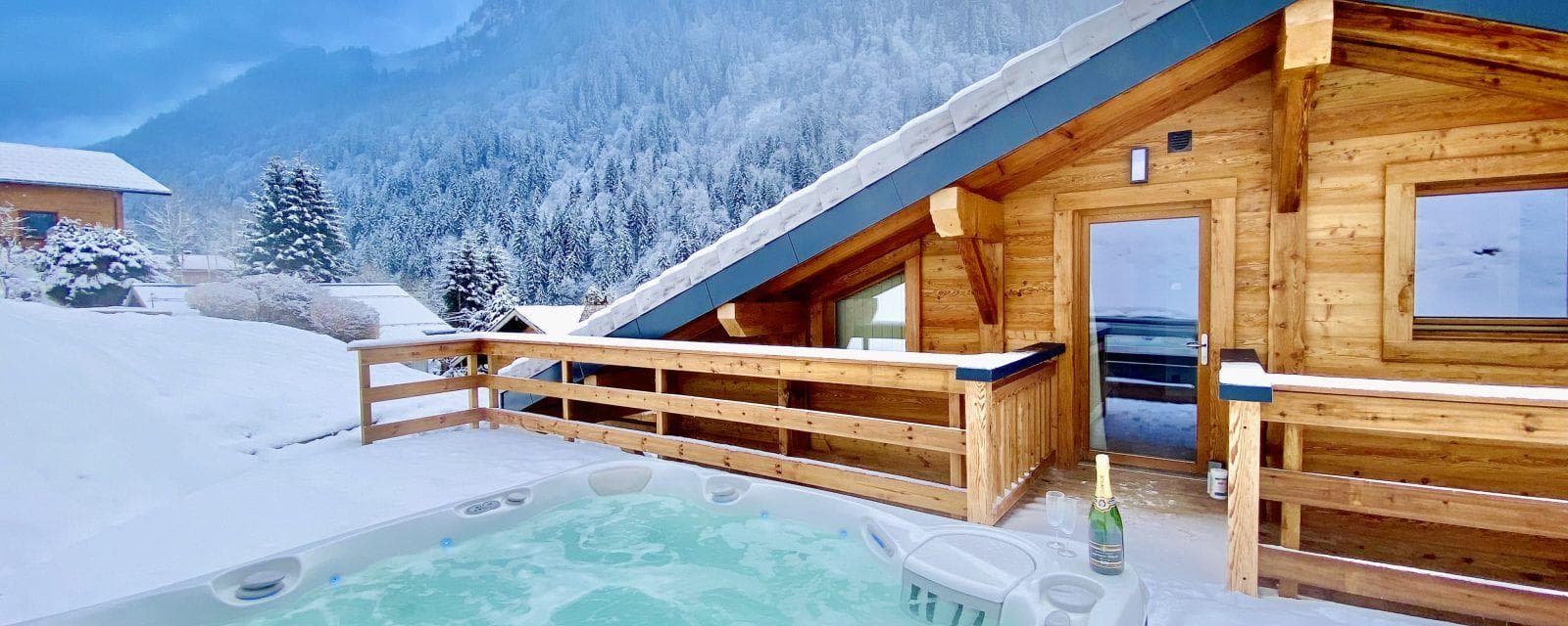 Outdoor hot tub with mountain views and wood chalet exterior