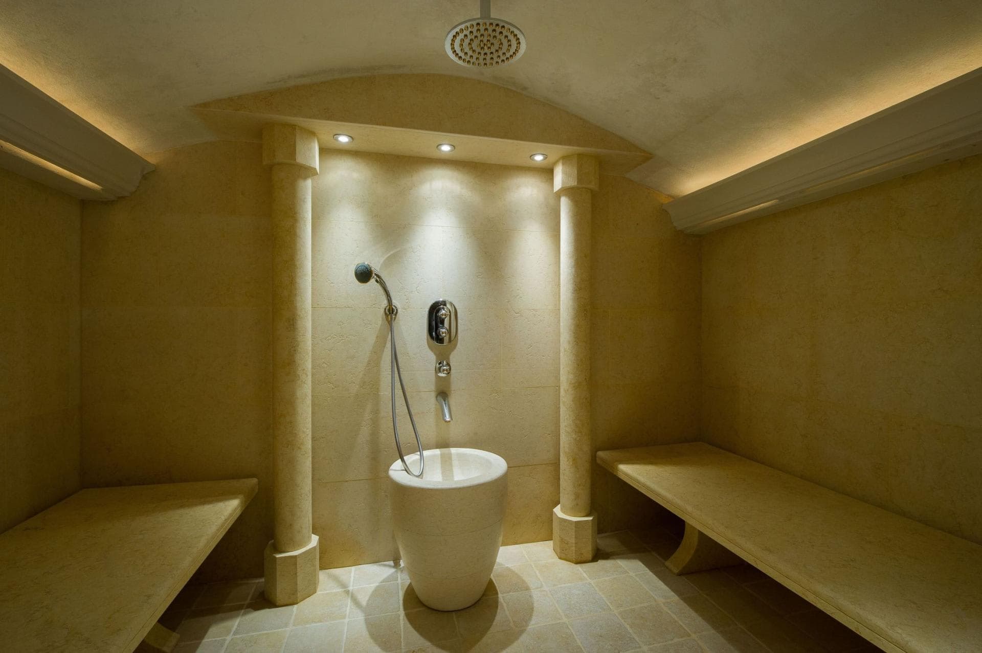 Stone hammam with rainfall shower and integrated bench seating