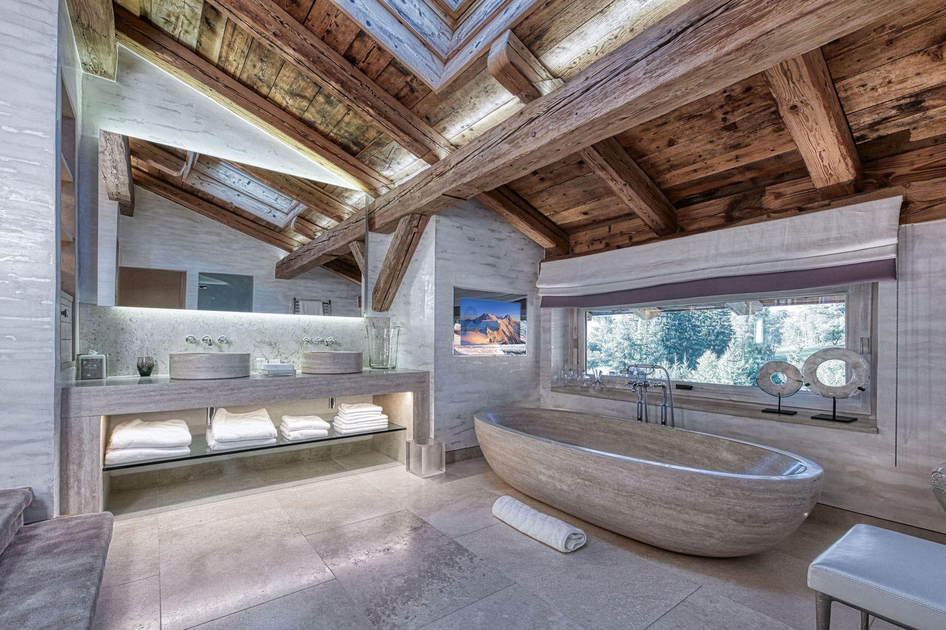Bathroom with dual stone vanities, freestanding soaking tub, and vaulted timber ceiling