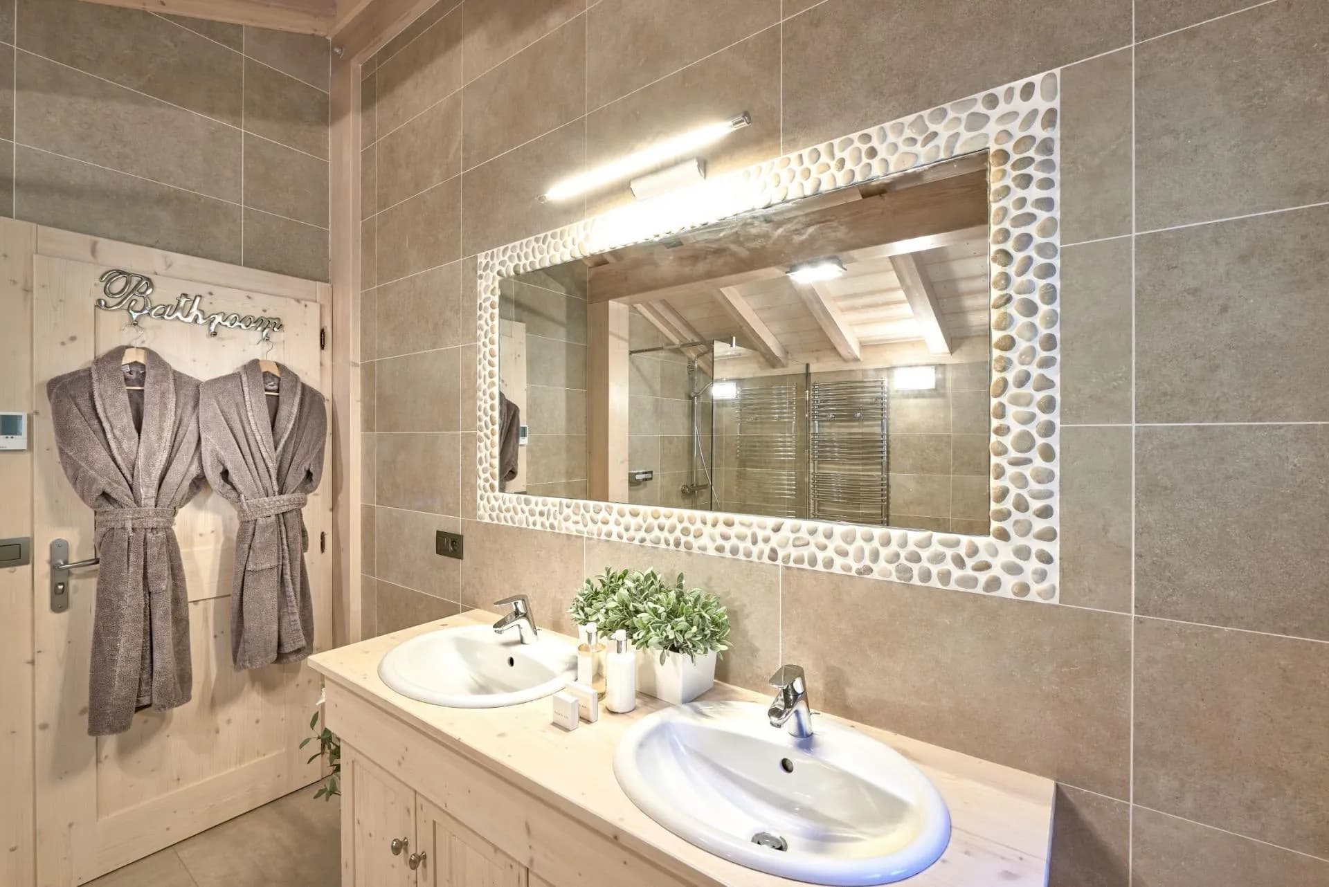 Bathroom with dual vanity, pebble-framed mirror, and heated towel rack
