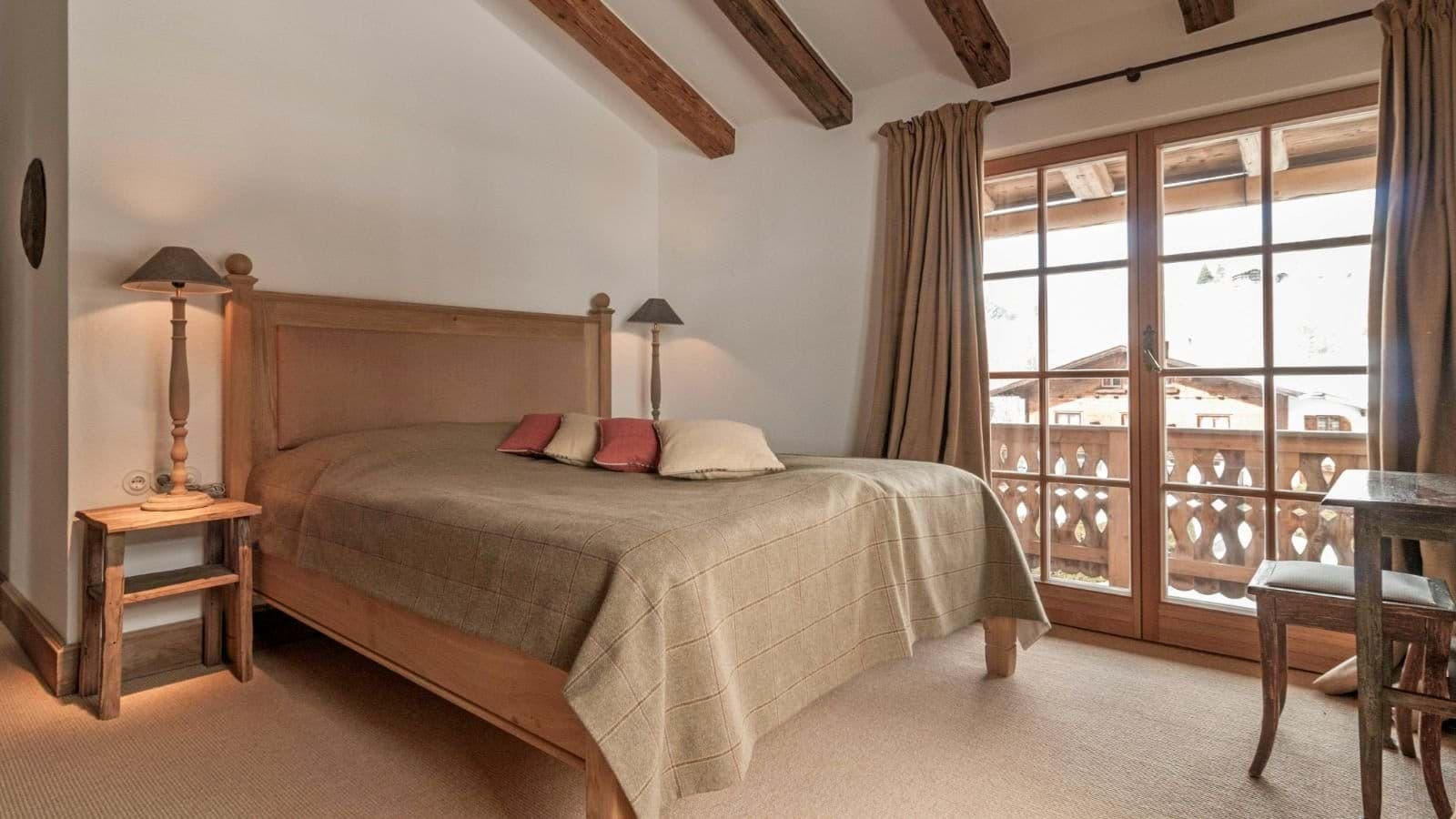 Guest bedroom with balcony access and exposed timber beams