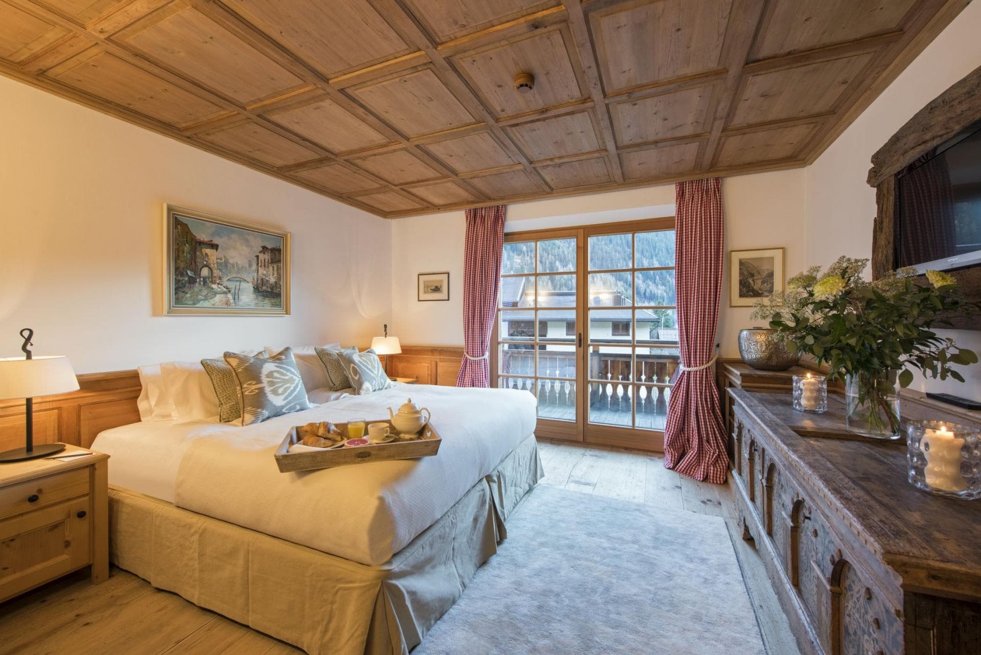 Bedroom with twin-to-king conversion, coffered wood ceiling, and balcony access