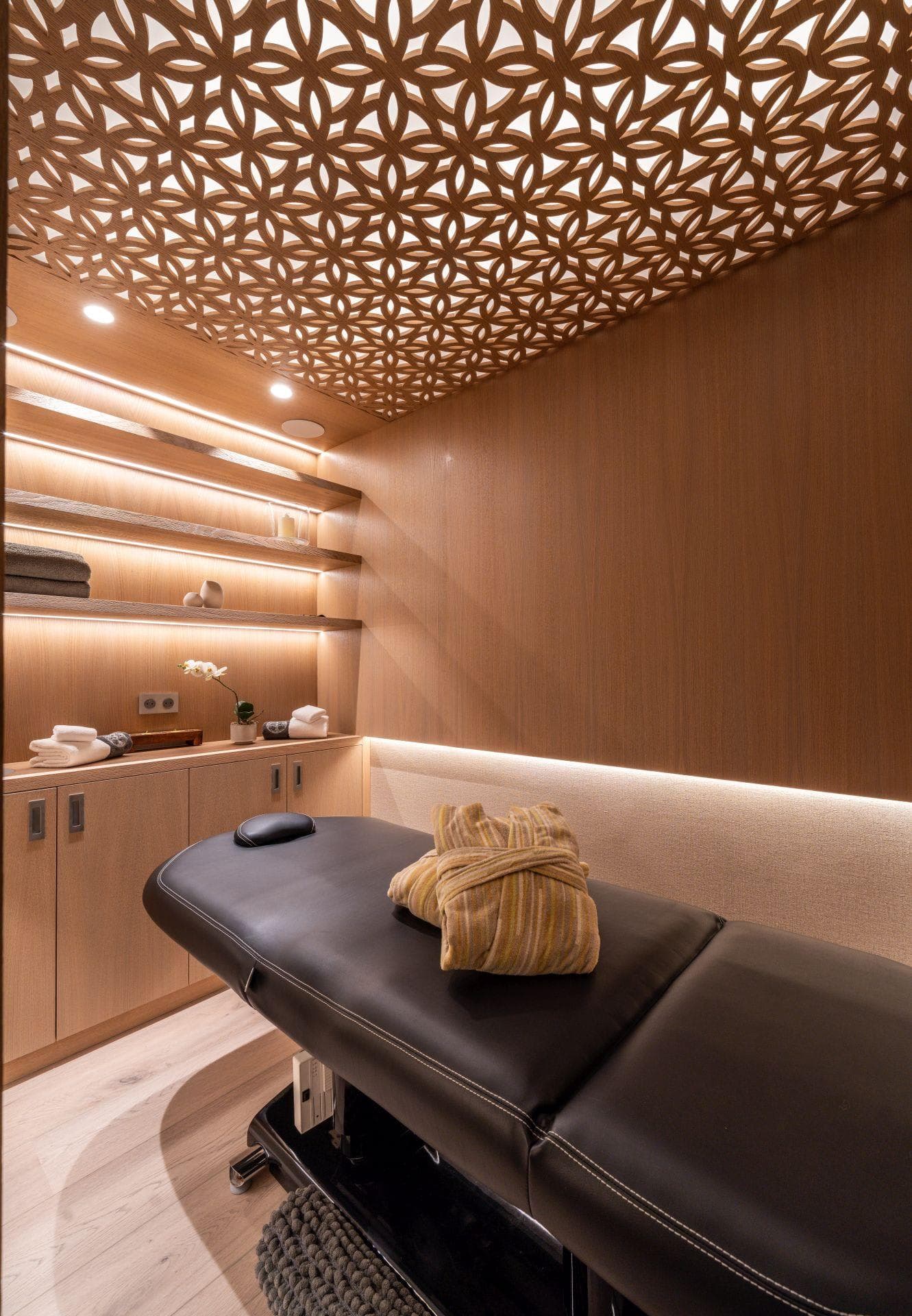 Private spa room with massage table and lattice light ceiling