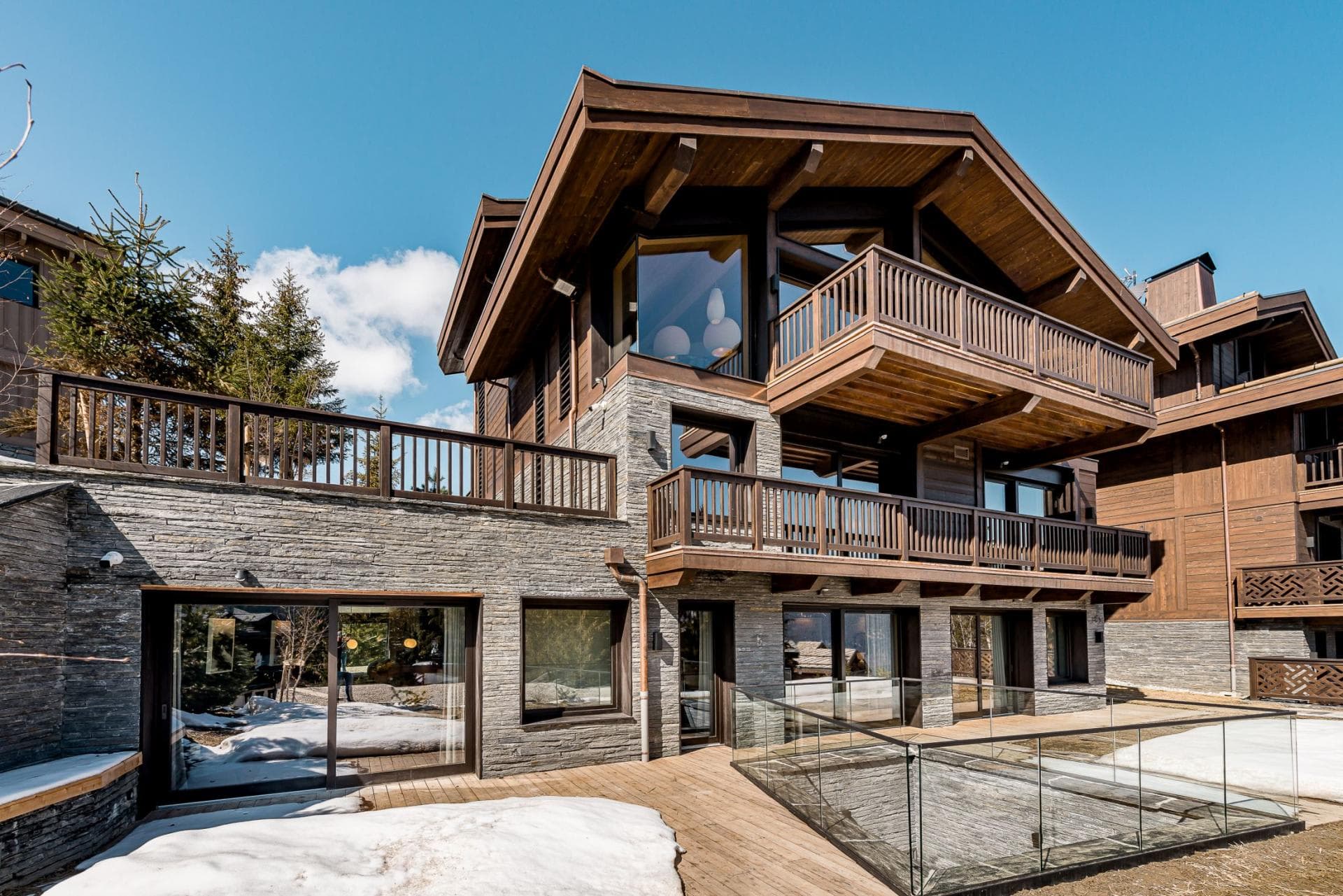 Chalet exterior with three levels of private balconies and stone masonry