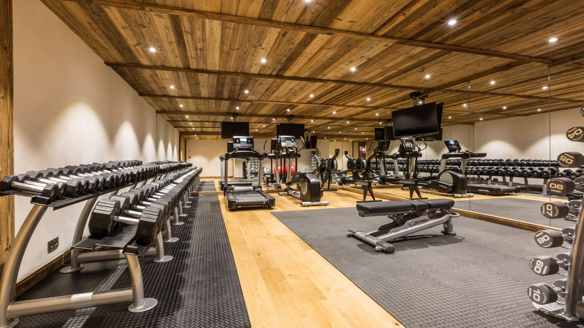 Private gym with cardio equipment, full dumbbell rack, and wall-to-wall mirrors
