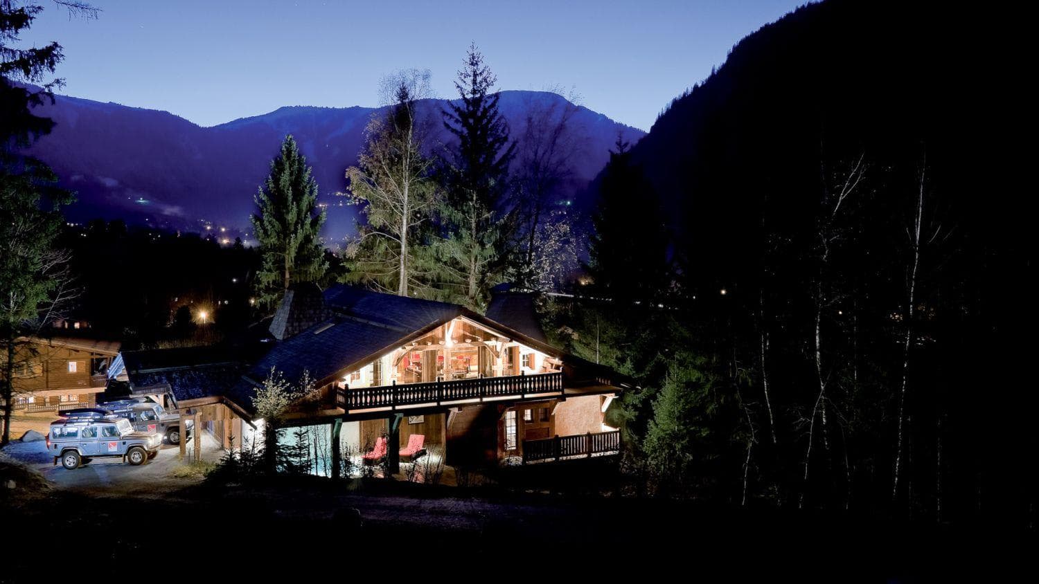 Chalet exterior at dusk with driveway parking and mountain valley views