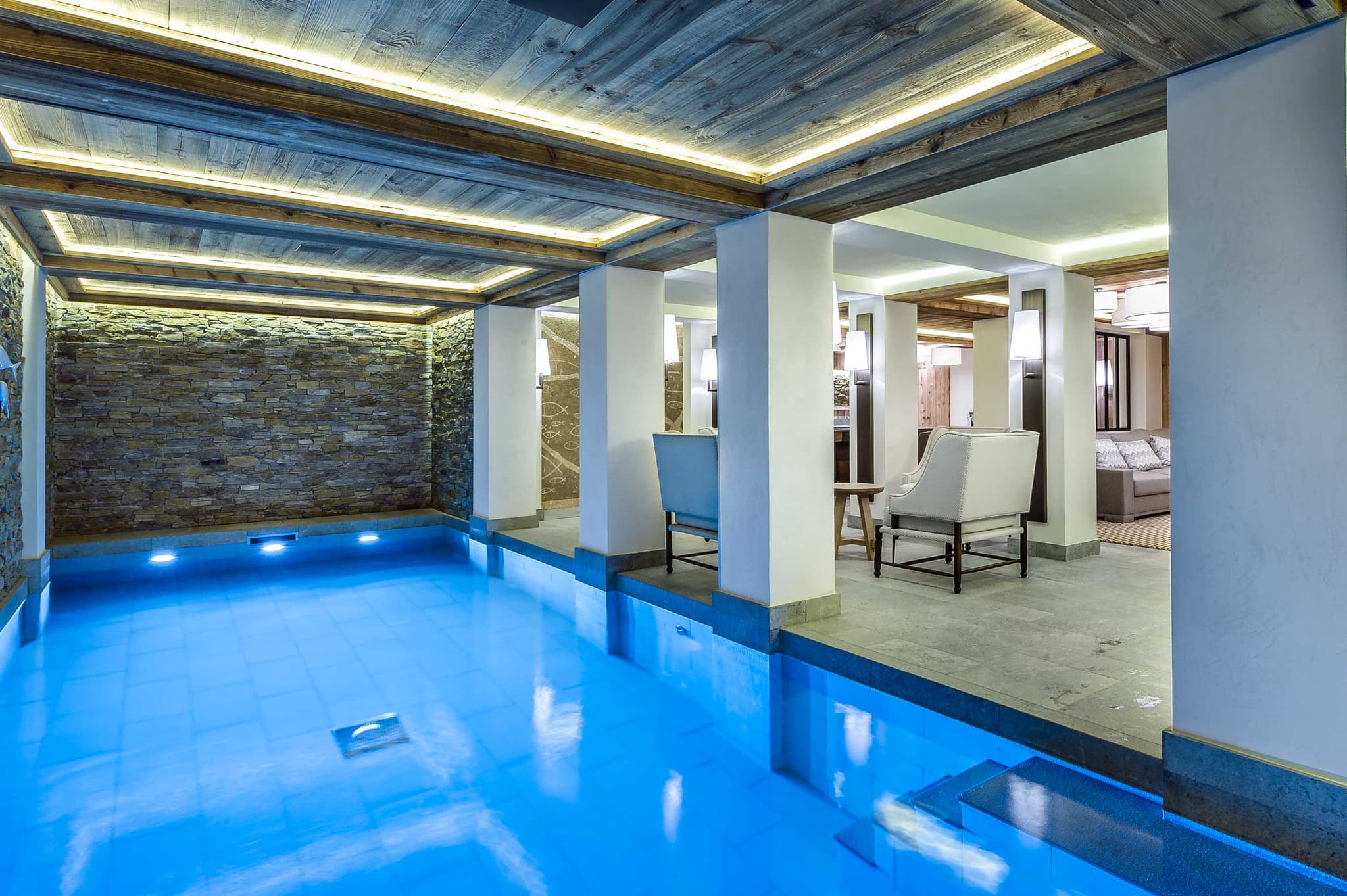 Indoor pool with stone feature wall and adjacent lounge seating
