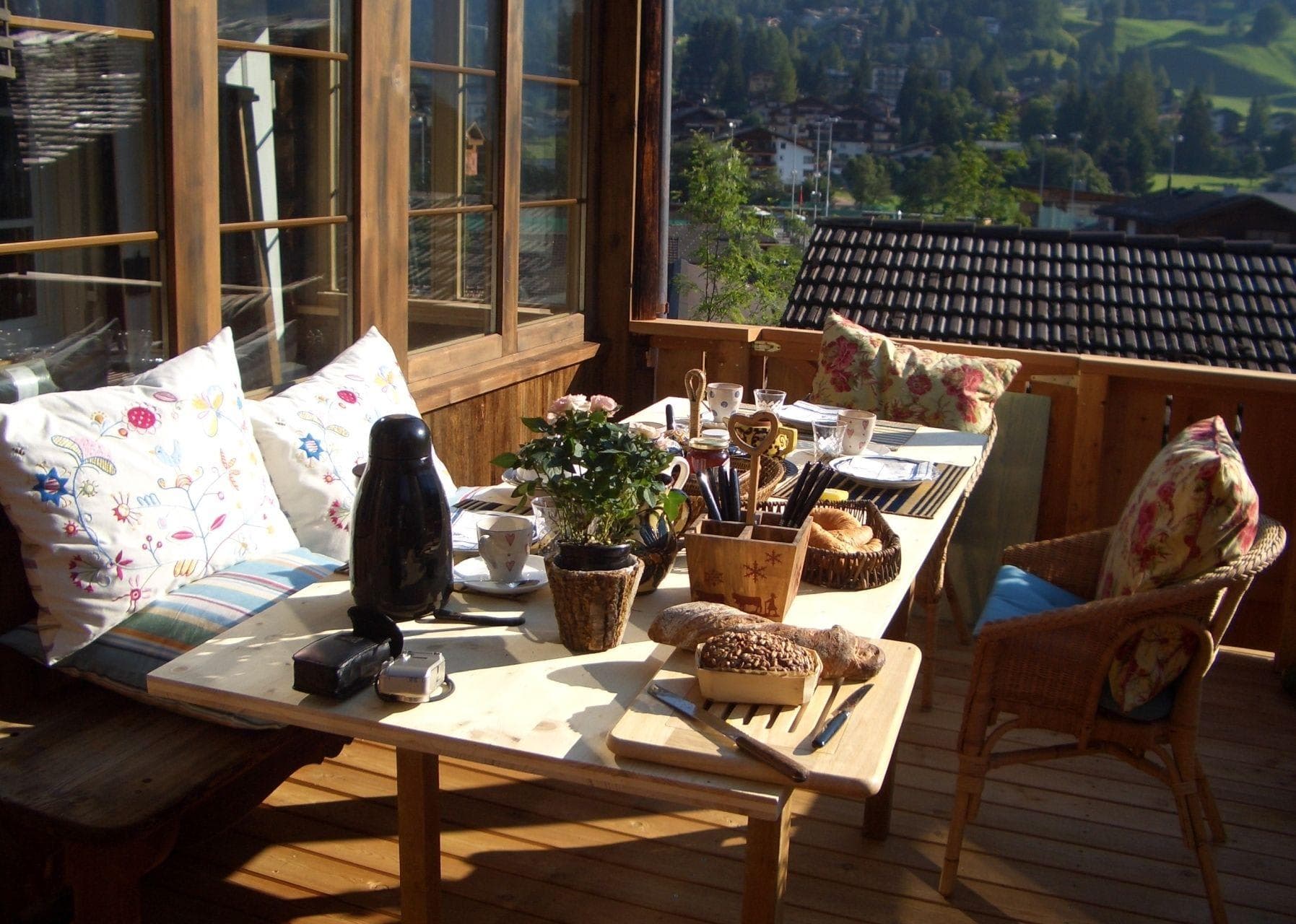 Private balcony with wooden dining table and alpine village views