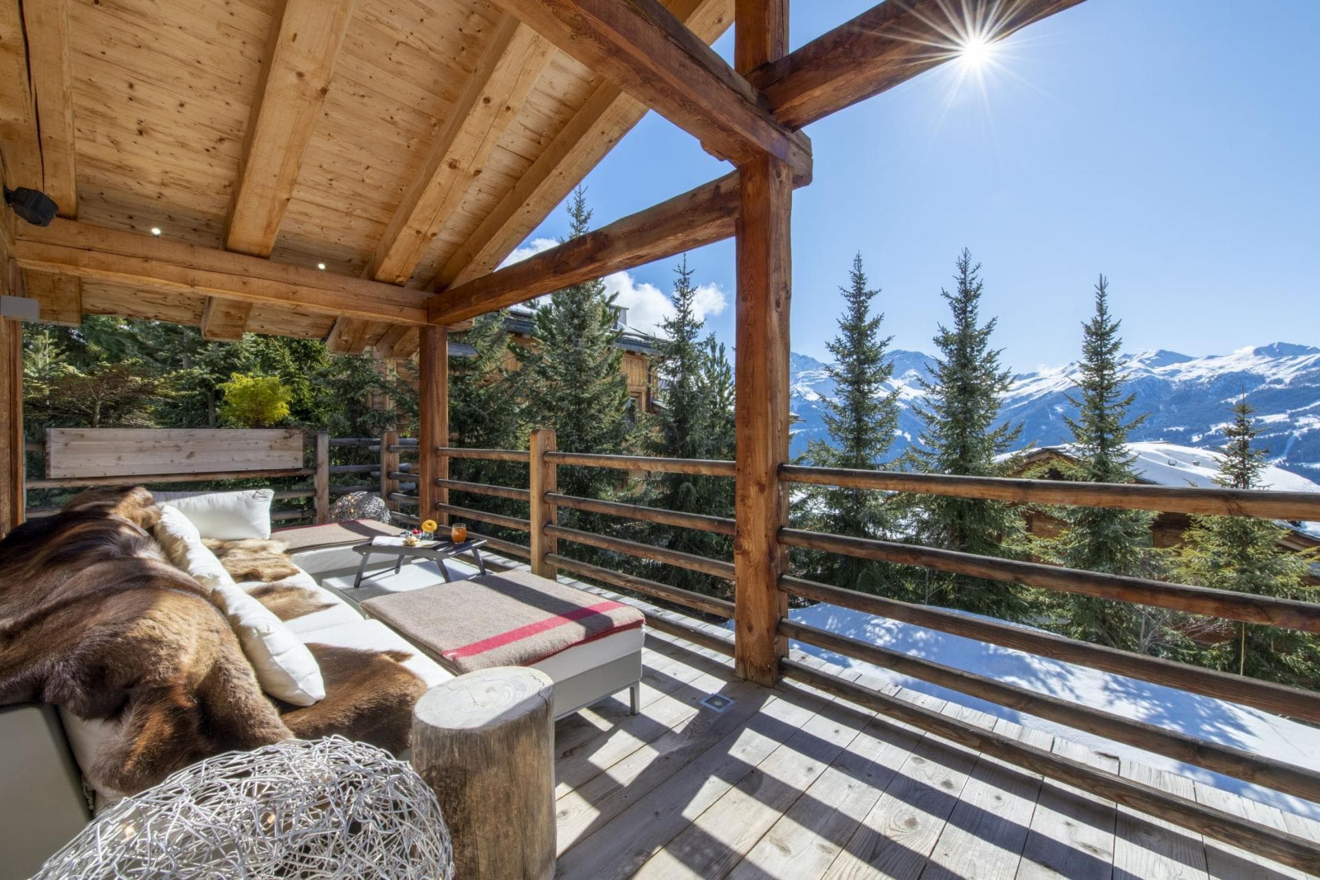 Covered timber balcony with daybed and panoramic Alps view