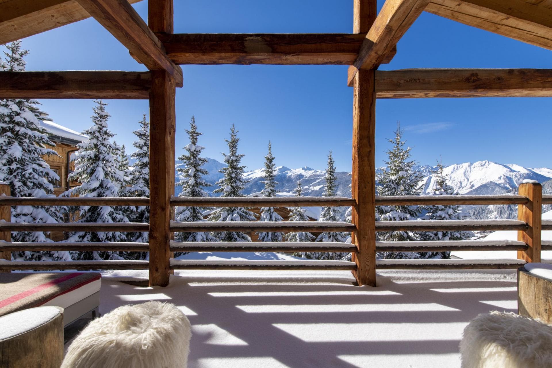 Covered timber balcony with south-facing mountain views and sheepskin seating