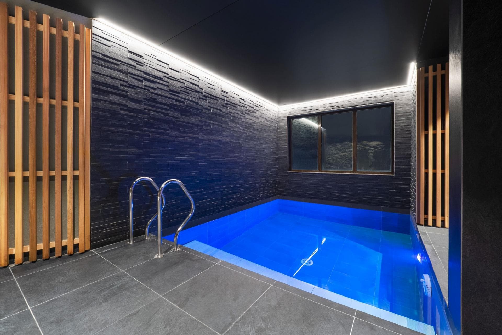 Indoor plunge pool with slate stone walls and integrated LED lighting