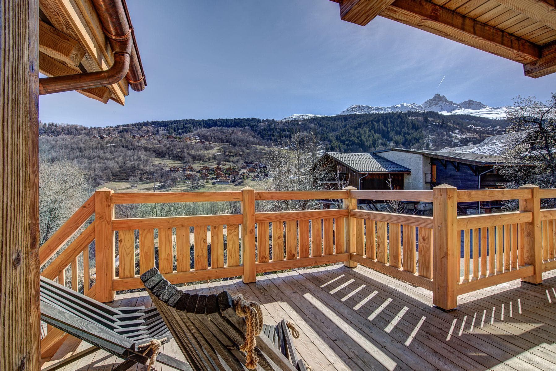 Wooden balcony with lounge chairs and views of snow-capped peaks