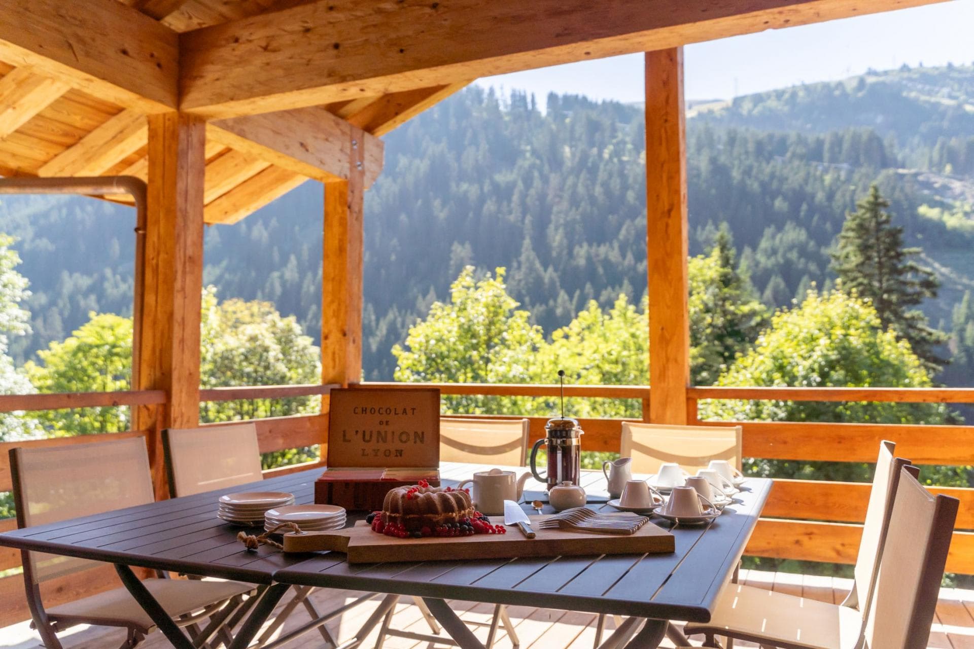 Covered timber deck with dining table and forest valley views