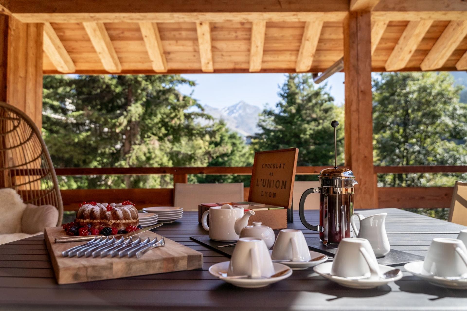 Covered outdoor terrace with dining table and mountain views
