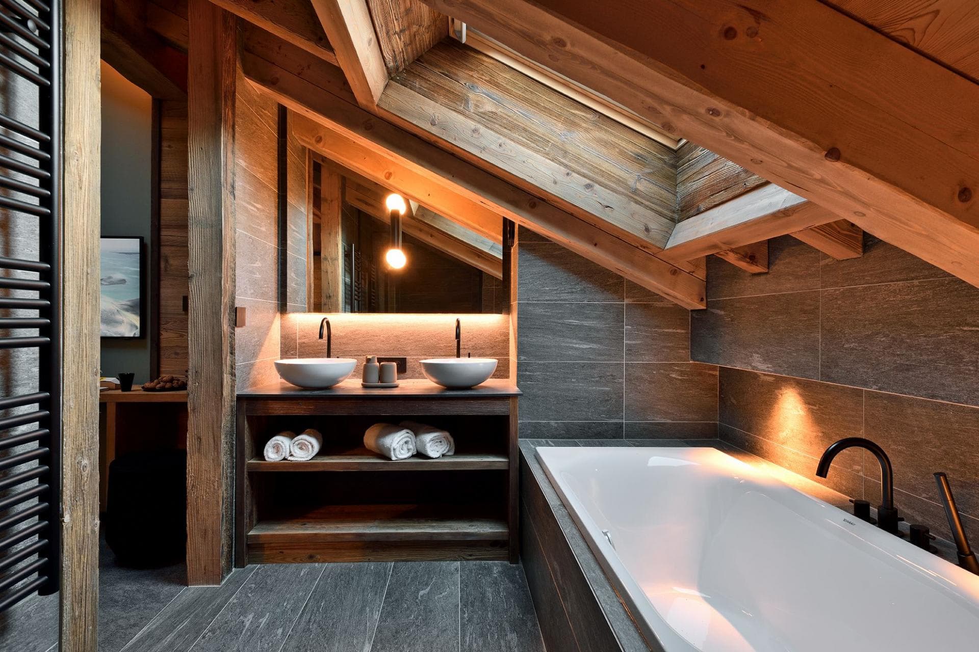 Primary bathroom with dual vessel sinks, soaking tub, and skylight; heated floors