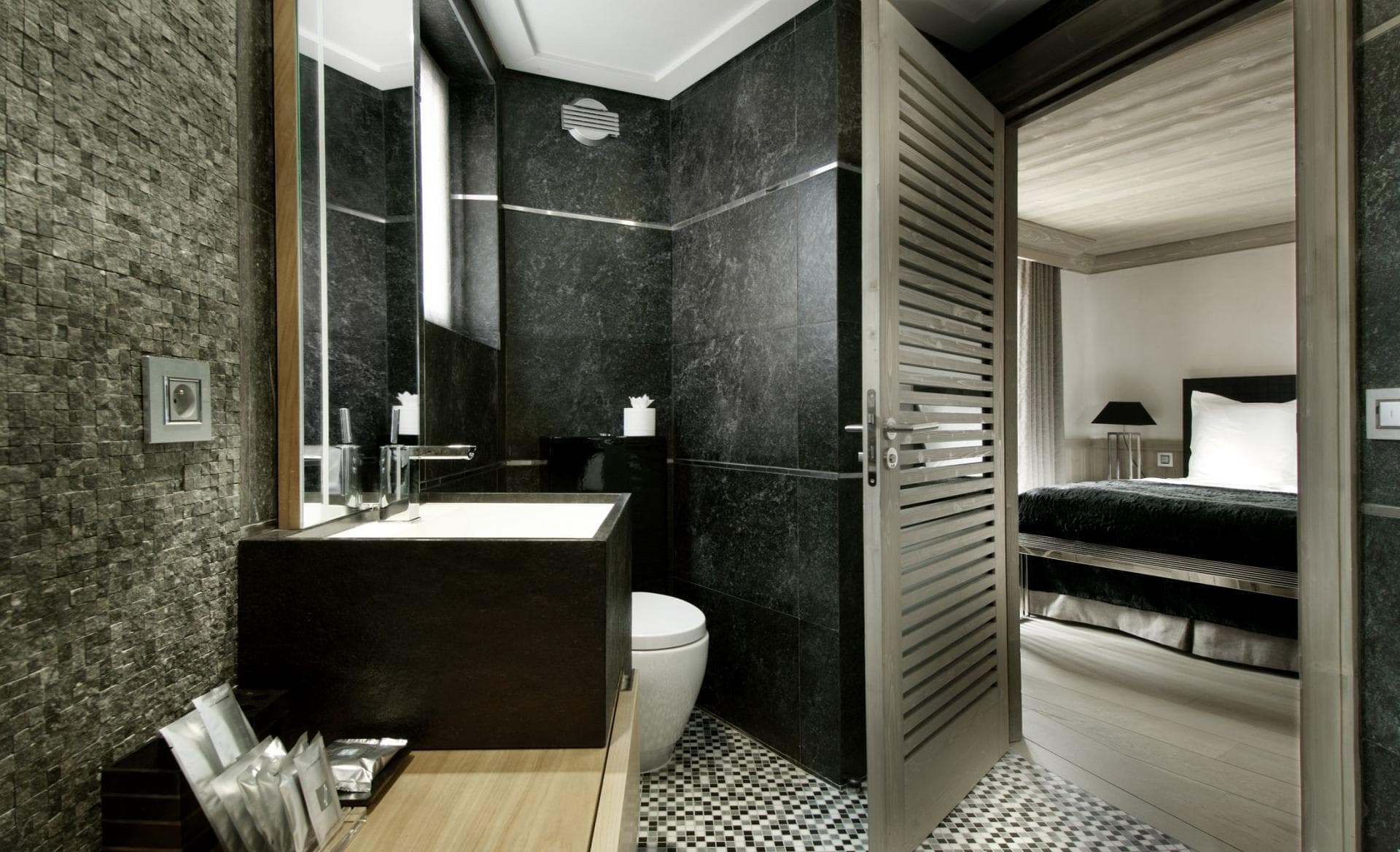 Ensuite bathroom featuring black stone walls and integrated block sink