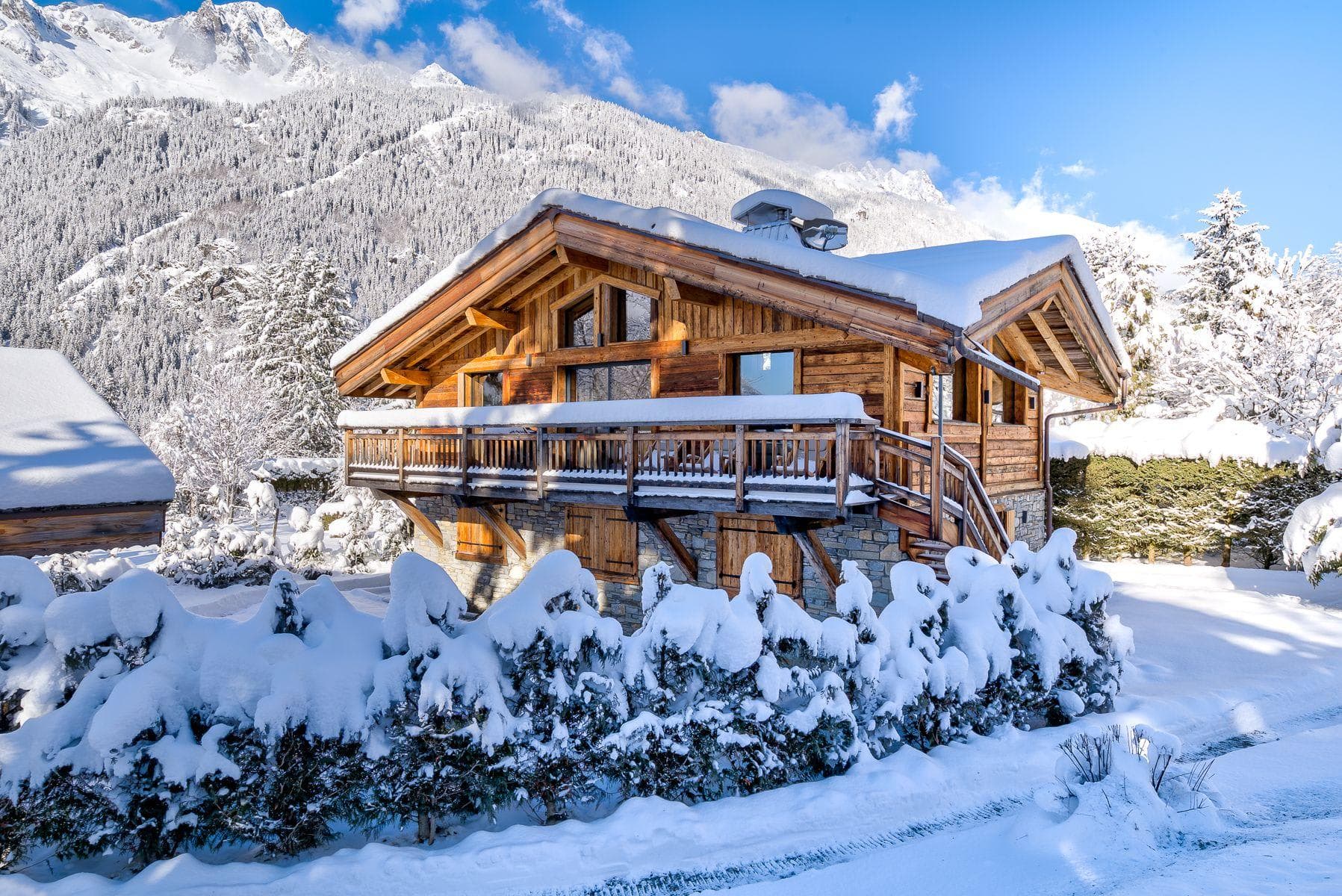 Wooden chalet exterior with wraparound balcony and mountain views