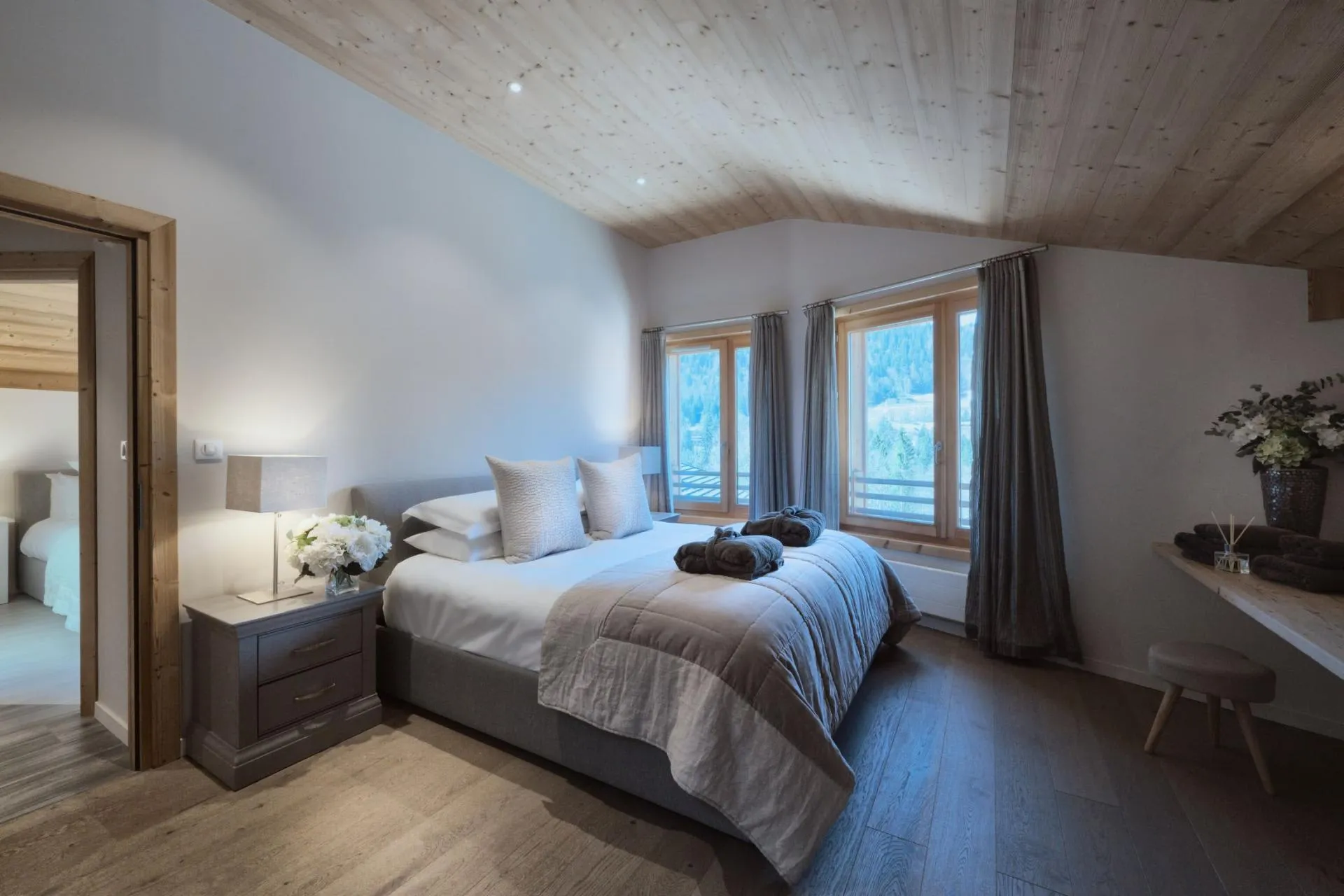 Bedroom with king bed and wood-paneled ceiling; forest views