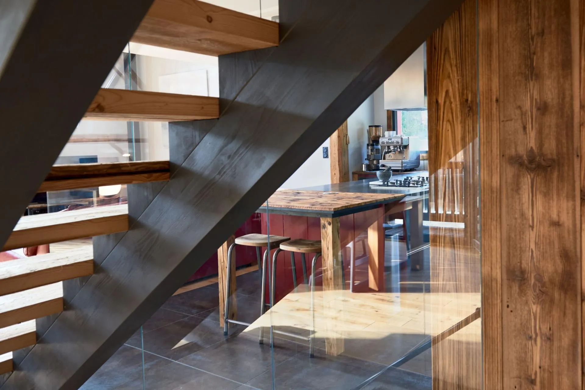 Fully equipped open kitchen with island seating beneath the glass staircase