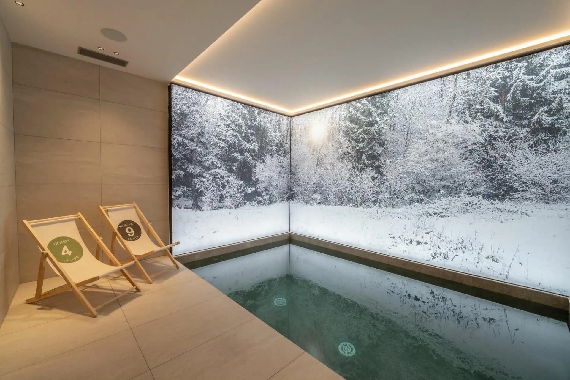 Indoor swimming pool with lounge chairs and woodland mural