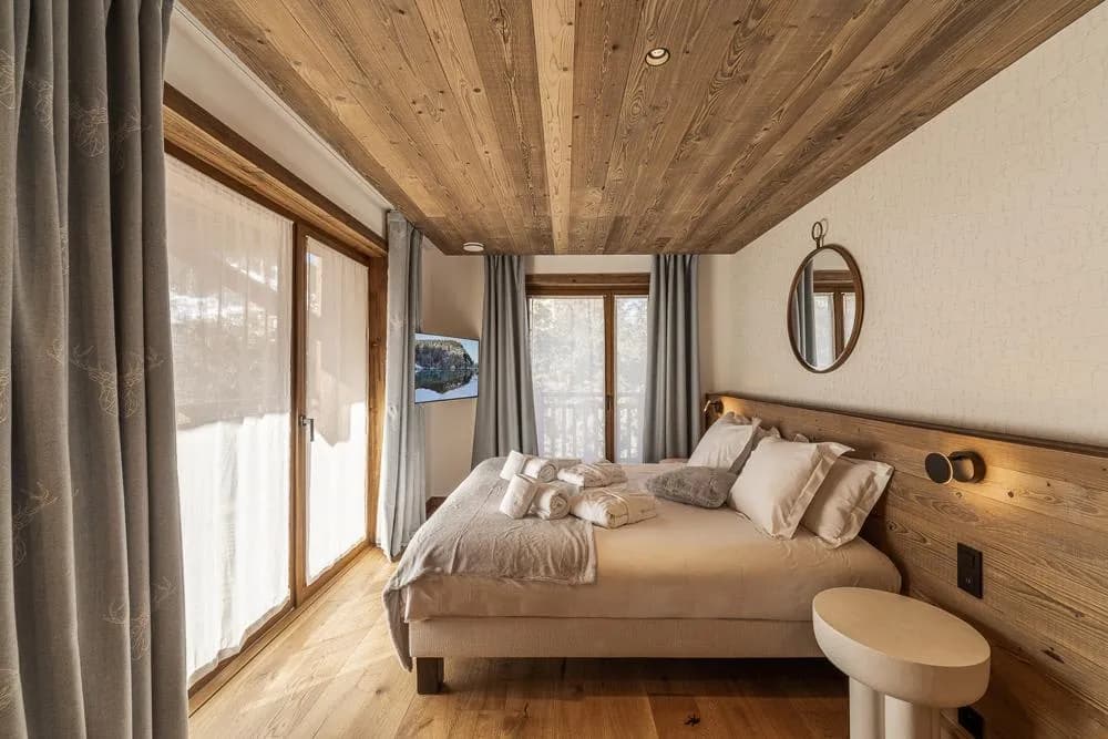 Double bedroom with timber ceiling and glazed doors