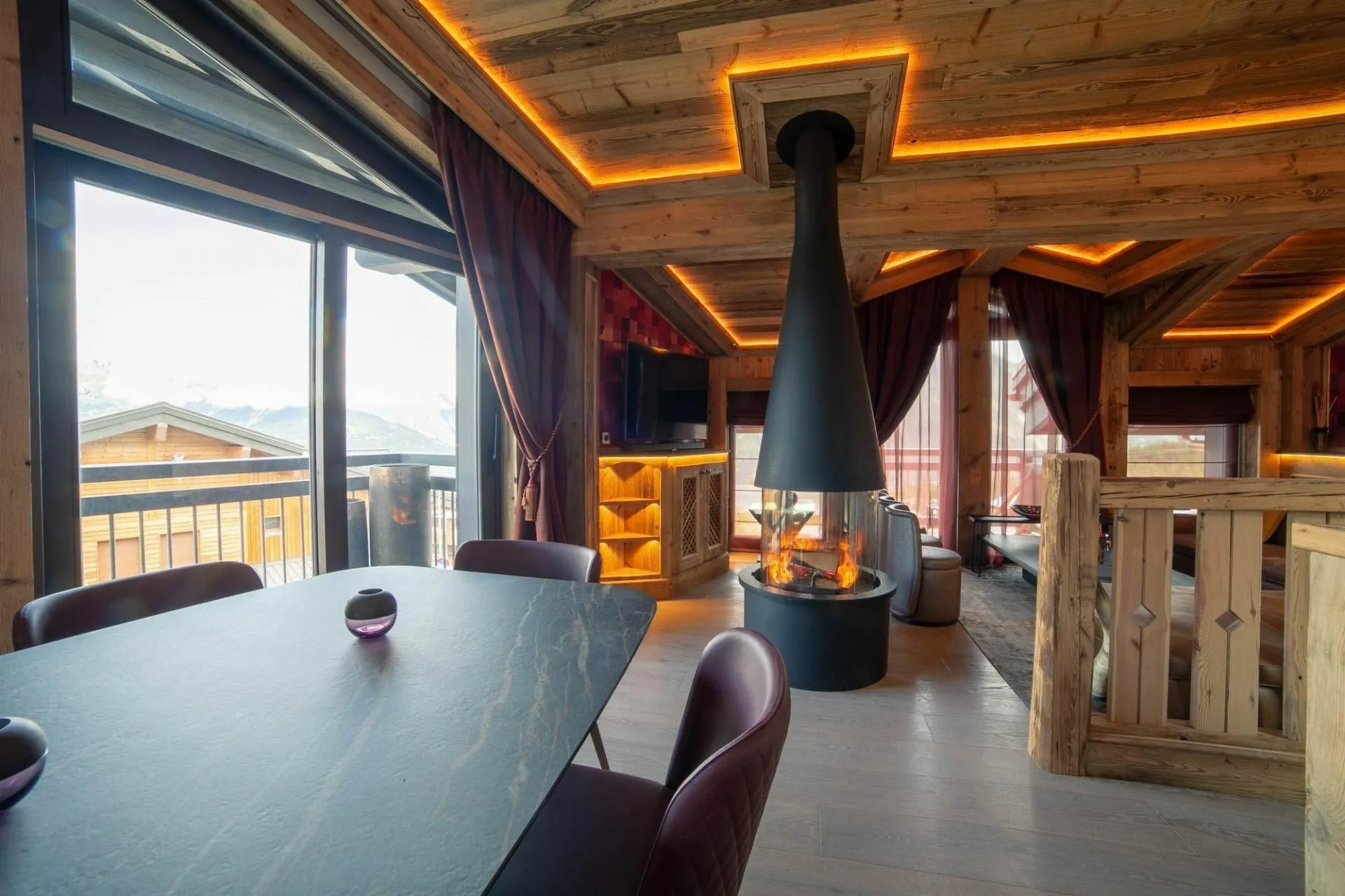 Living and dining floor with suspended fireplace and mountain-facing windows