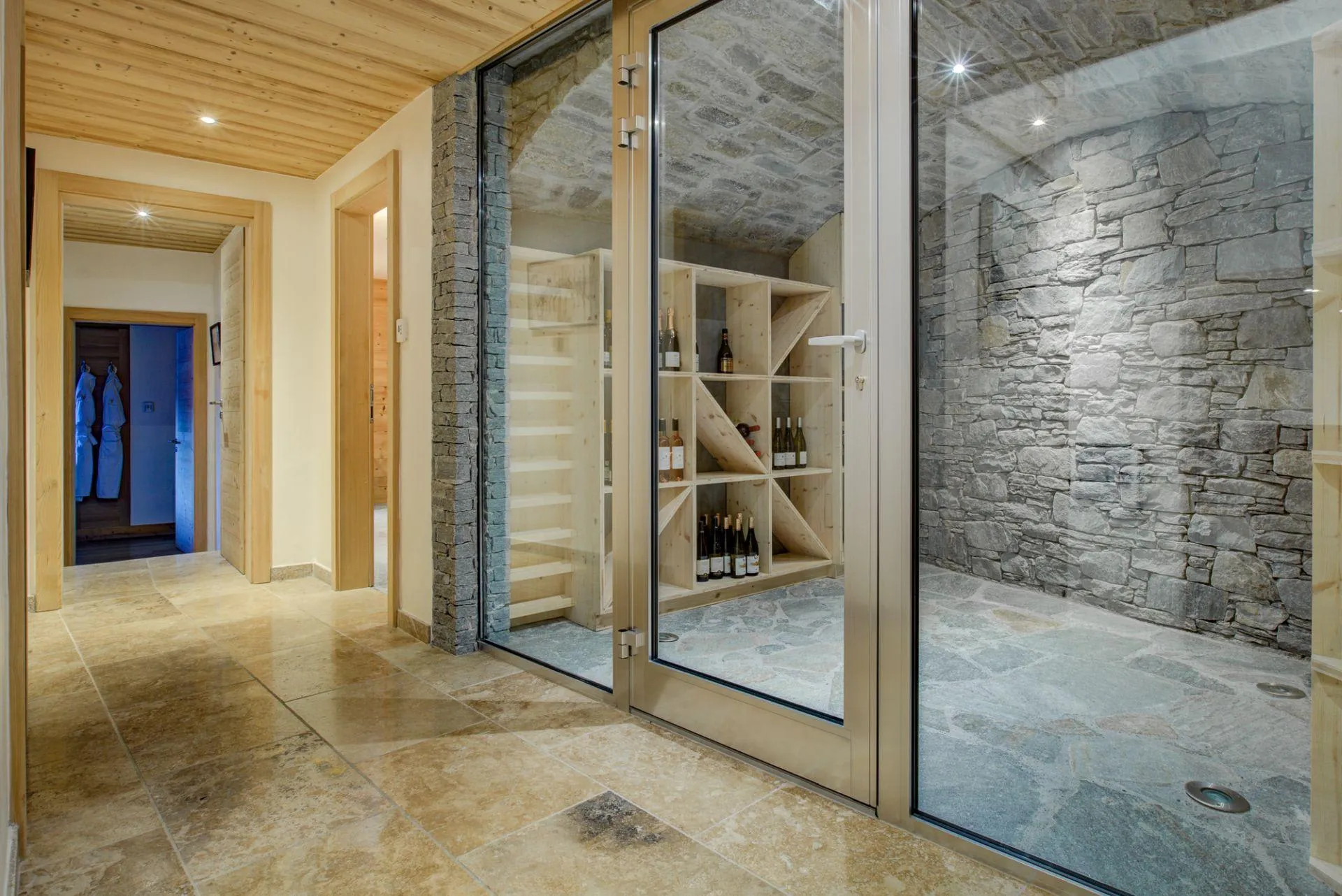 Glass-fronted wine cellar with natural stone walls