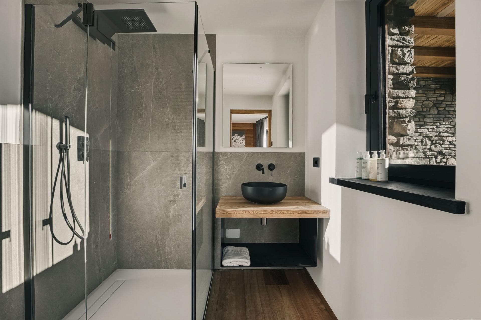 Bathroom with rainfall shower head and stone-tile walls