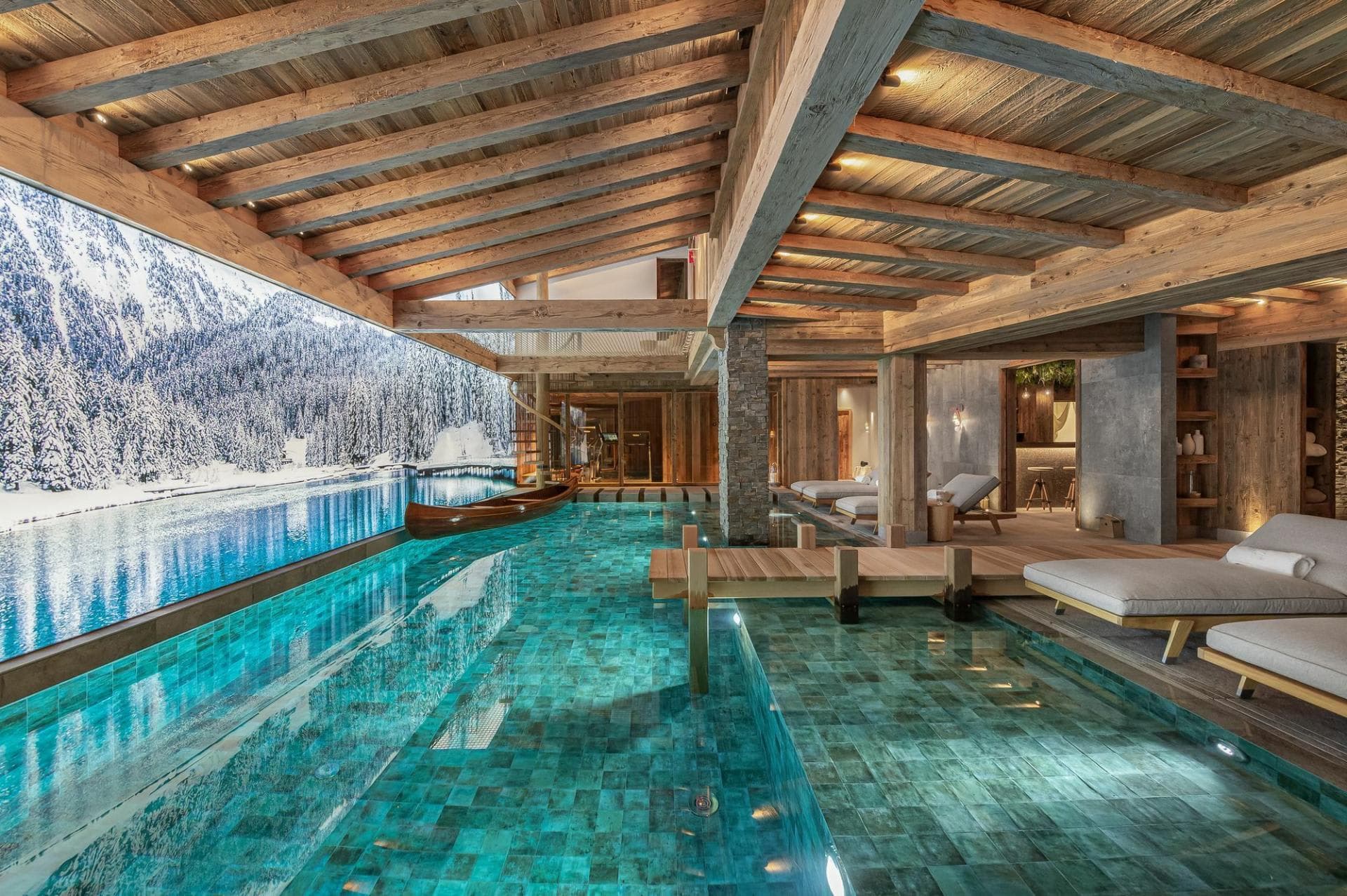 Indoor pool with wooden dock and snowy mountain lake views