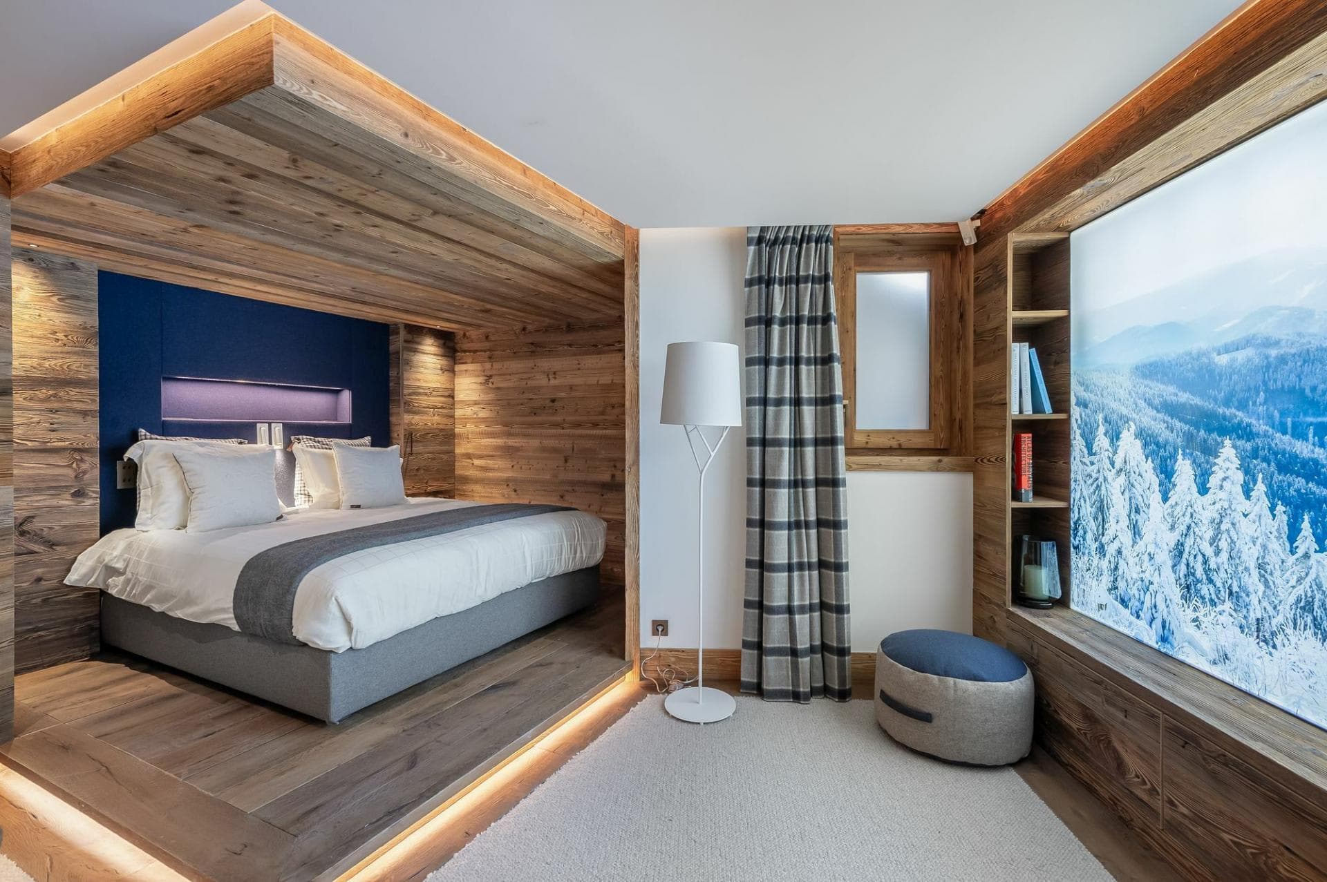 Wood-paneled sleeping alcove with king bed and snowy mountain views