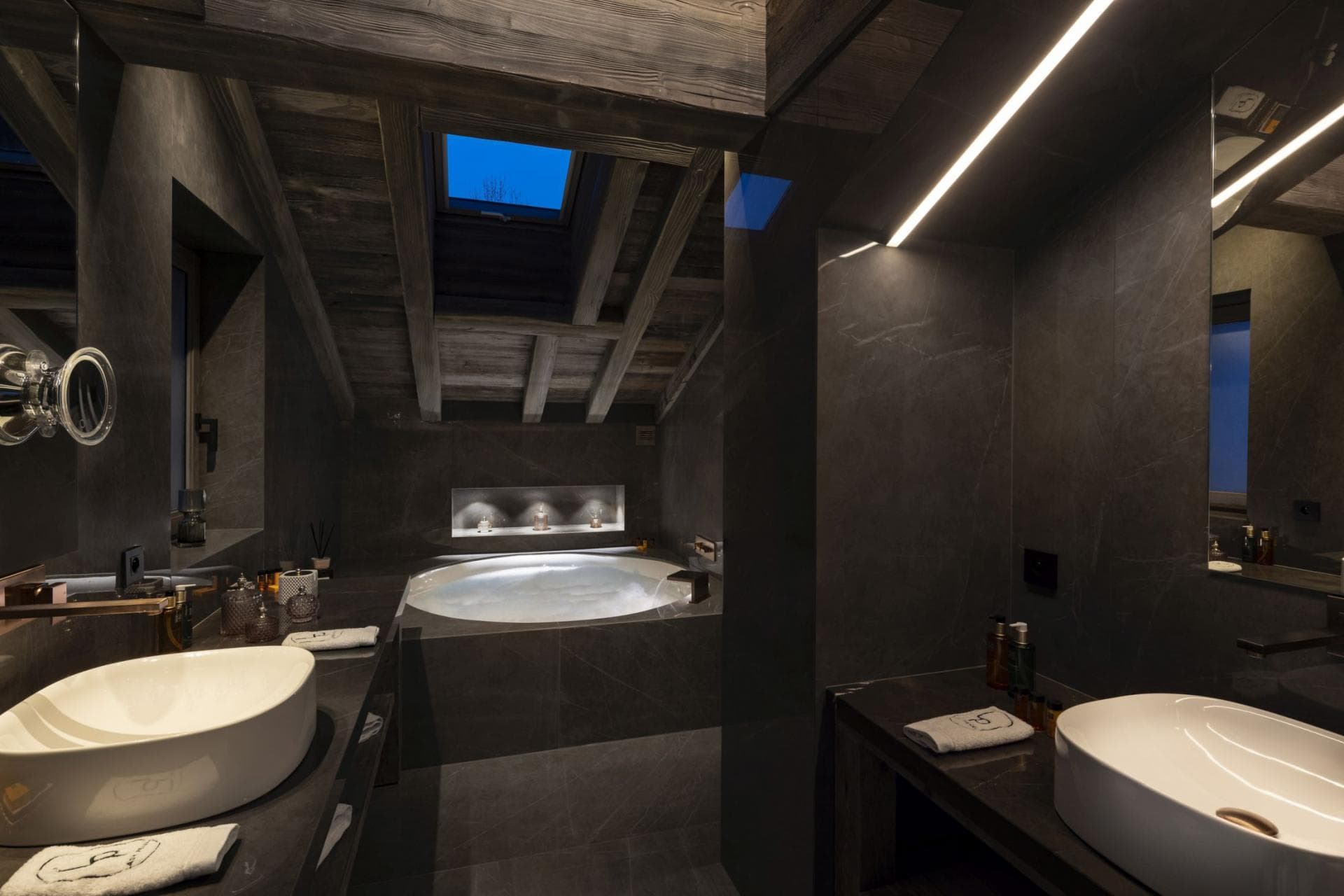 Bathroom with dual vessel sinks, soaking tub, and skylight