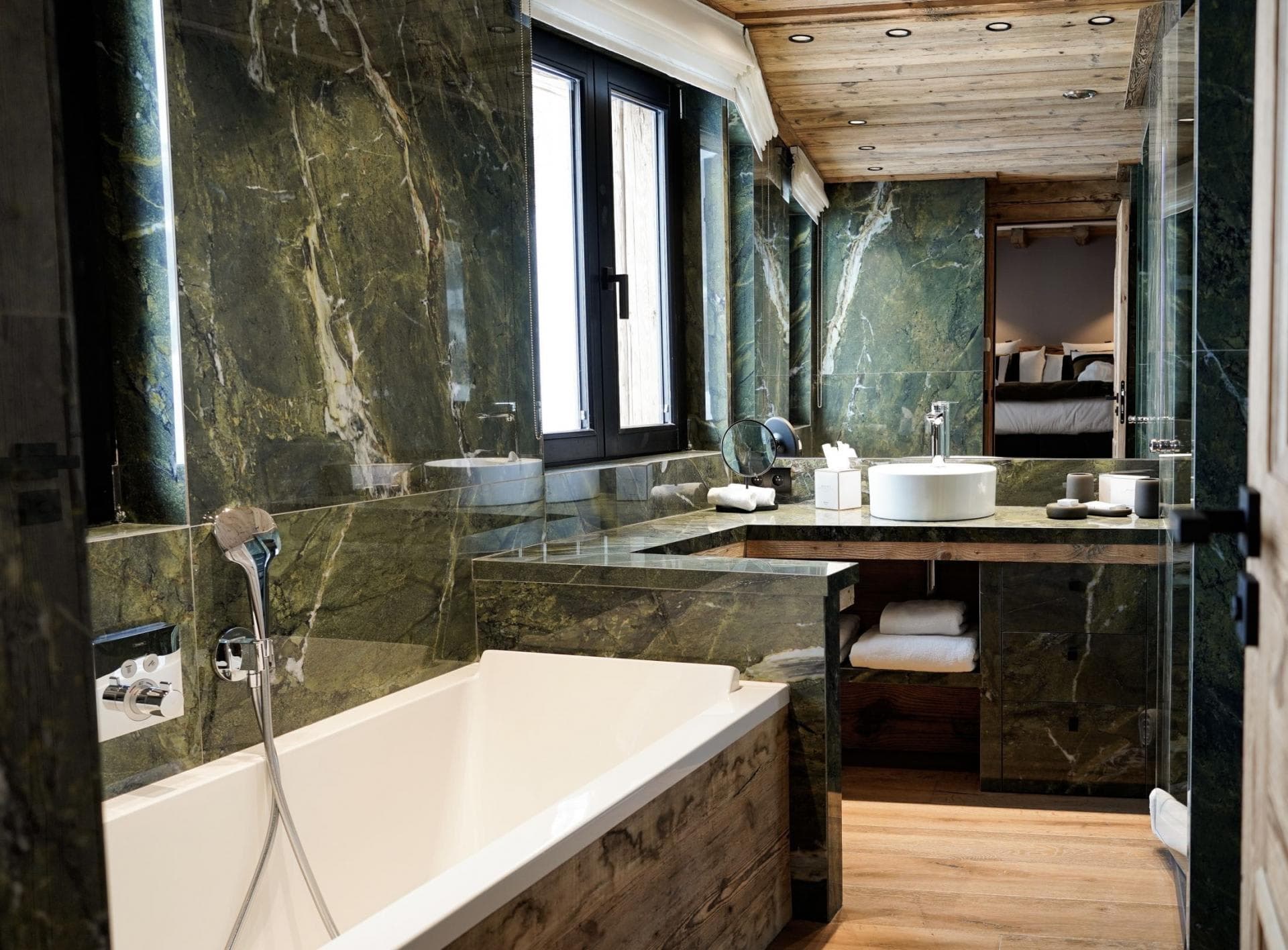 Ensuite bathroom featuring green marble walls and soaking tub