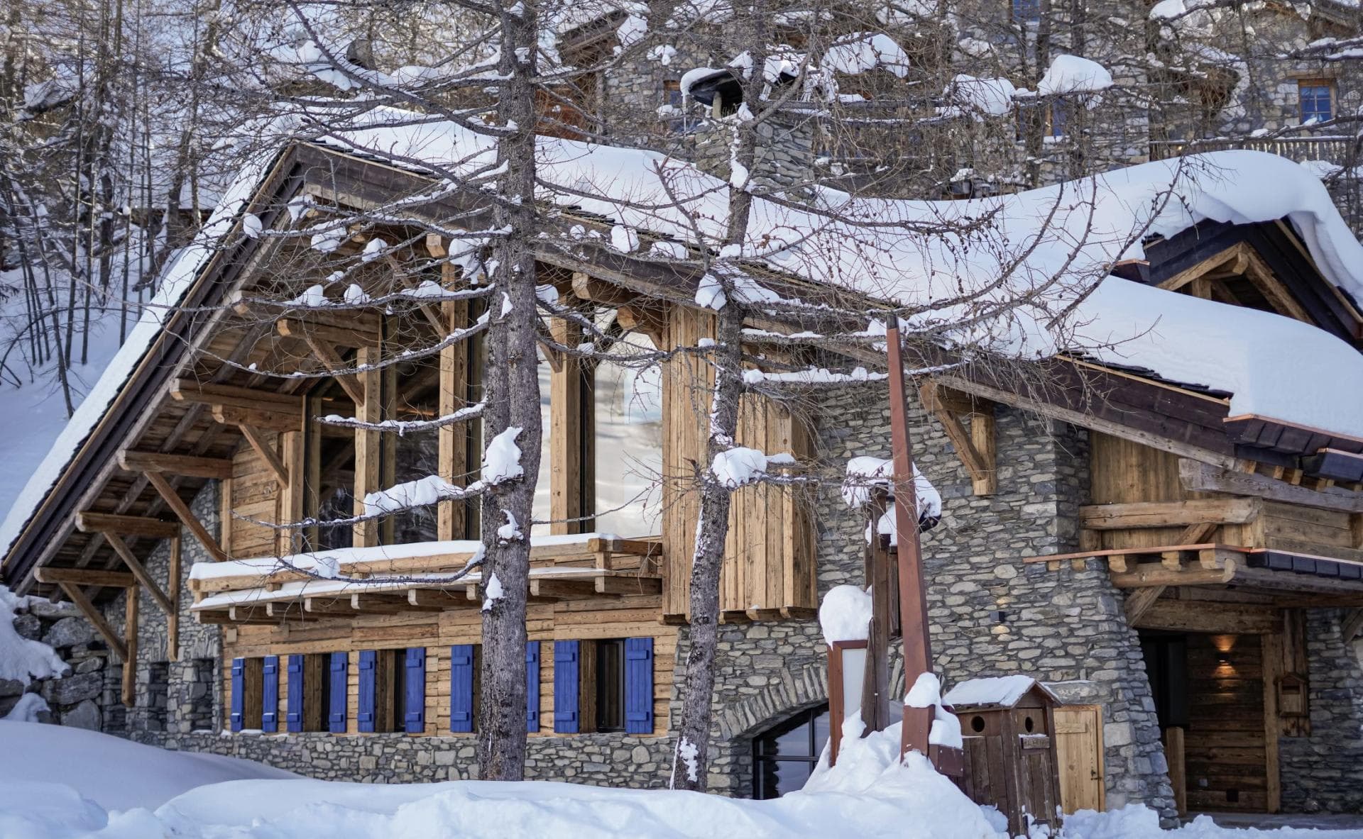 Alpine chalet exterior with stone masonry and floor-to-ceiling upper level windows