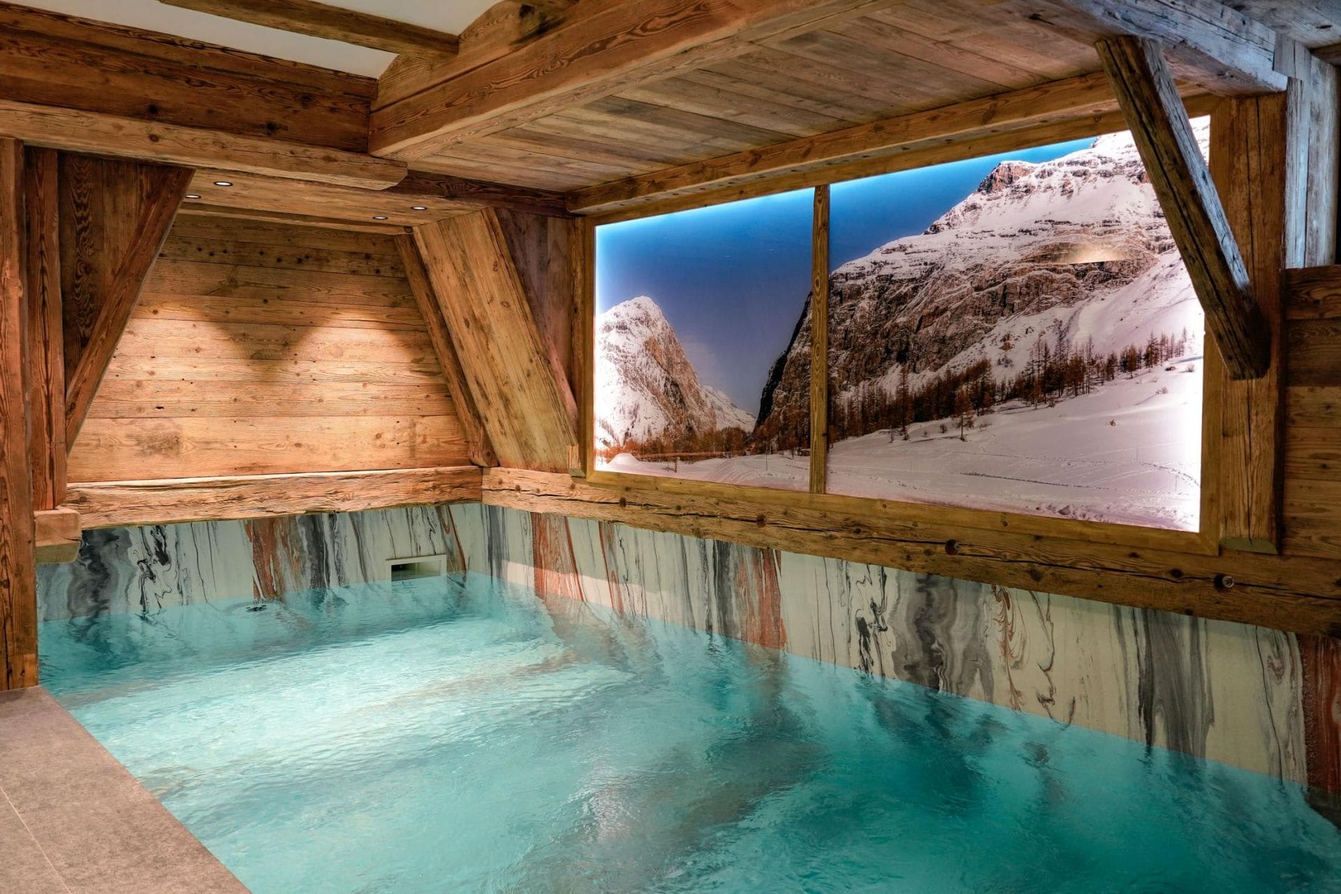Indoor pool with reclaimed timber beams and mountain backdrop