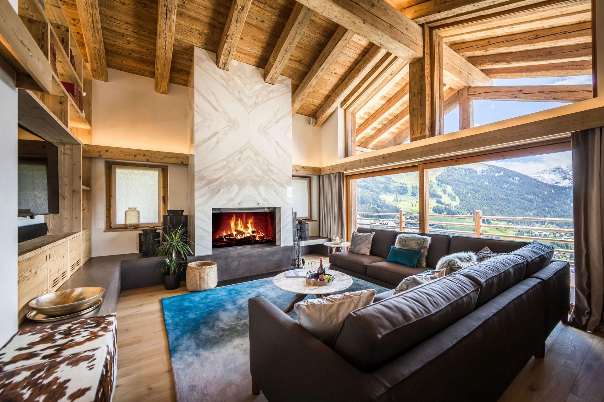Living area with wood-burning fireplace and floor-to-ceiling mountain views