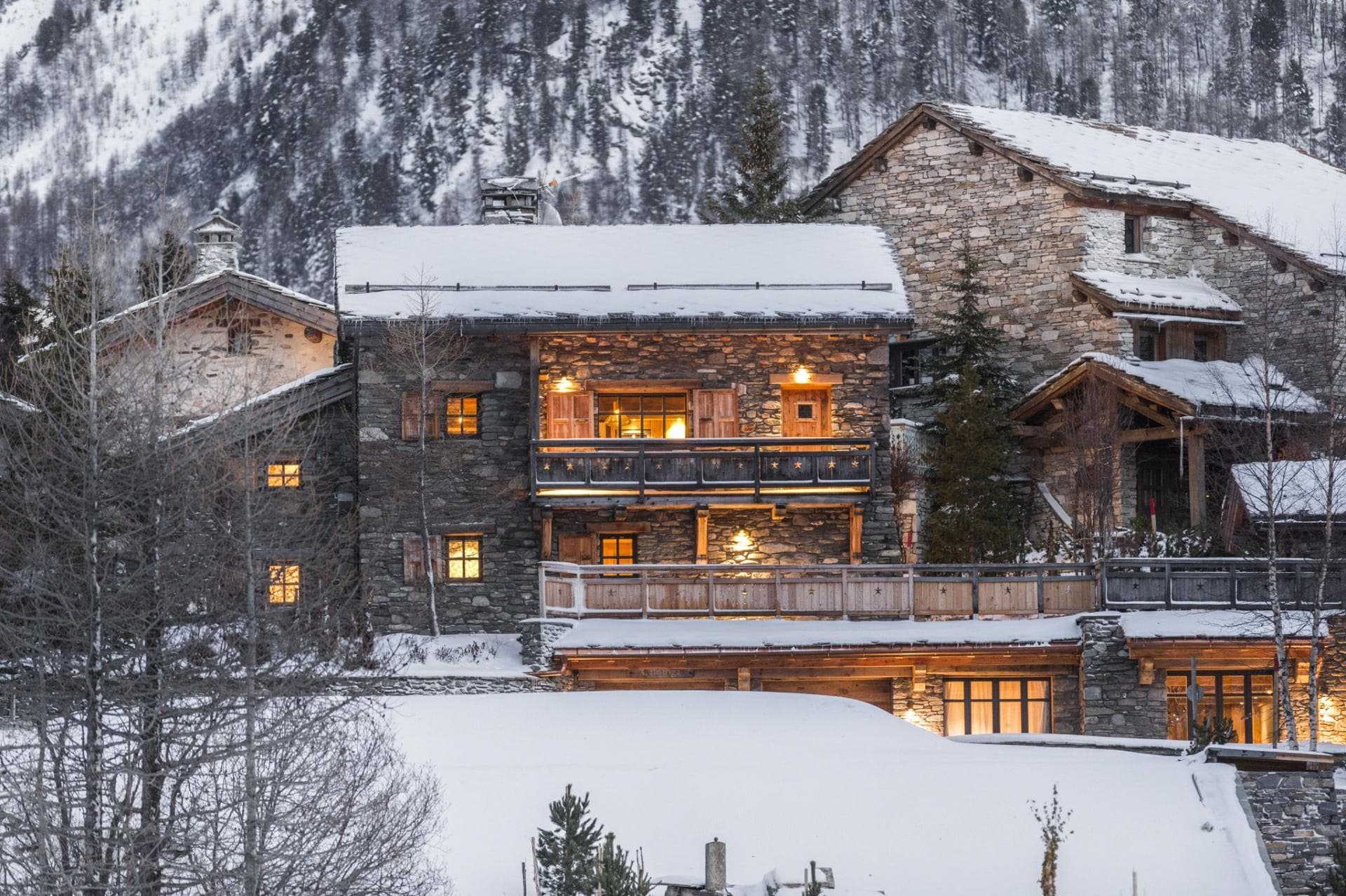 Stone chalet exterior featuring private balconies and mountain backdrop