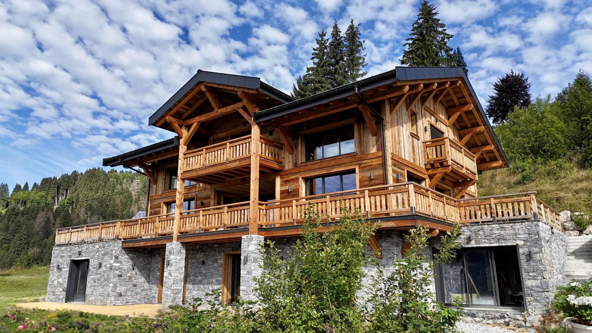 Timber chalet with stone base and wrap-around balconies over three levels