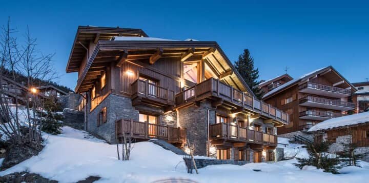 Ski-in chalet exterior with multiple private balconies and stone masonry