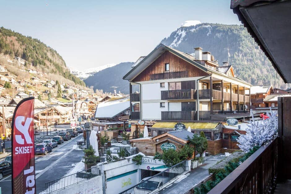 Balcony view overlooking village center and mountains; steps from ski rentals